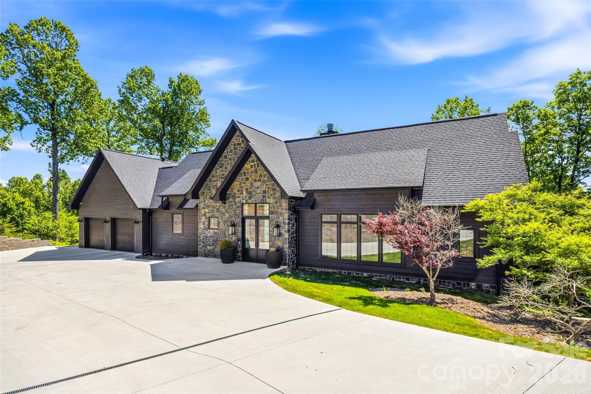 Modern mountain exterior with stone accents, dramatic rooflines, covered entry, and three-car garage. - 241 Tower Circle, Hendersonville