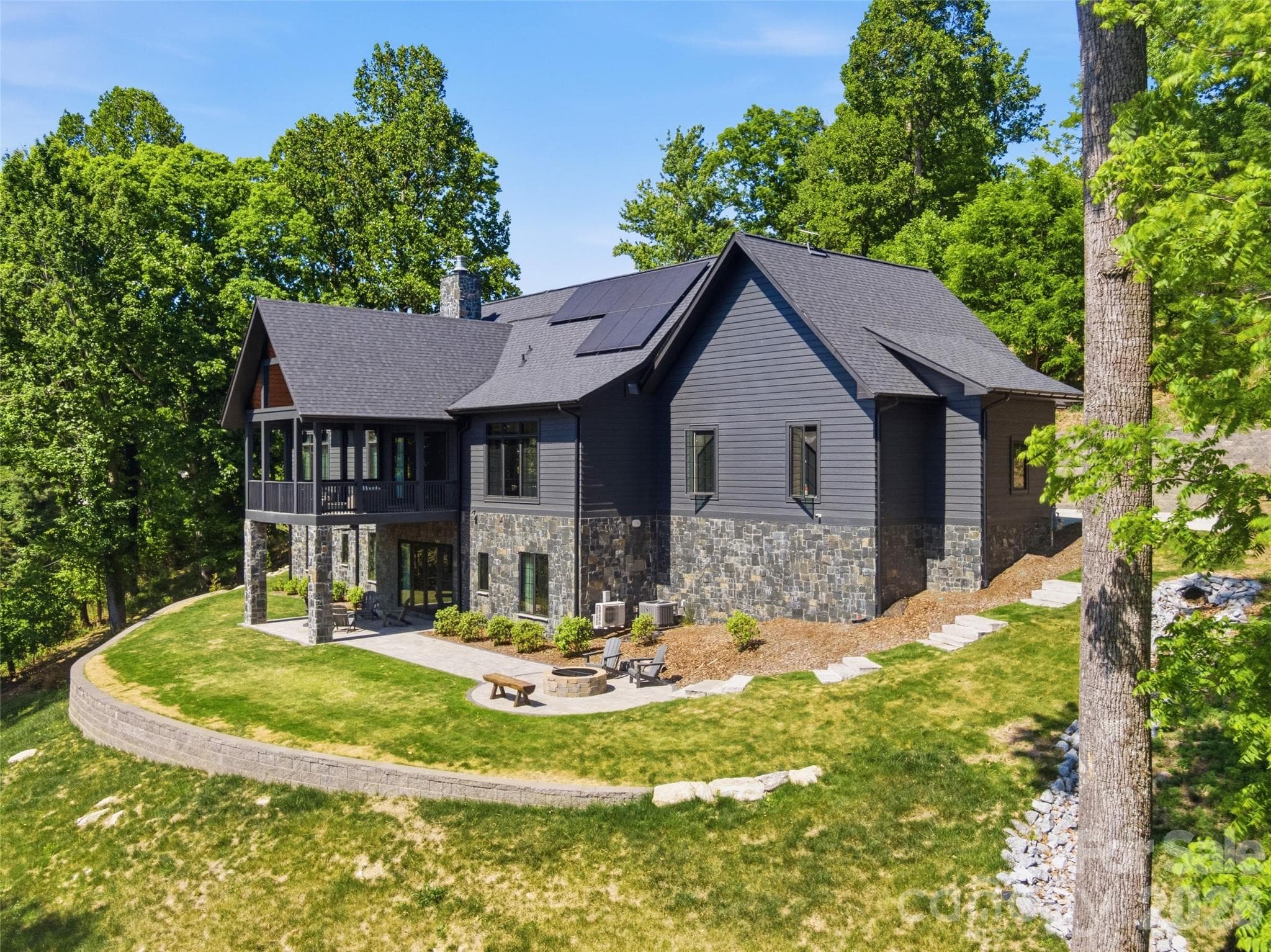 Rear exterior featuring stone accents, covered deck, and terrace-level patio - 241 Tower Circle, Hendersonville