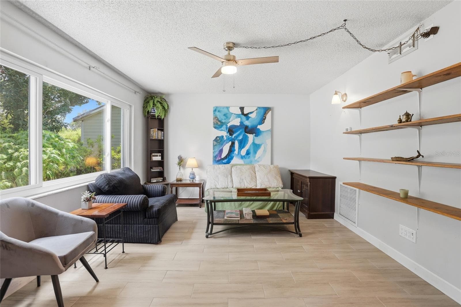 Living room with a large front window, tile flooring, and open wall shelving. - 804 ROSALIA DR, SANFORD