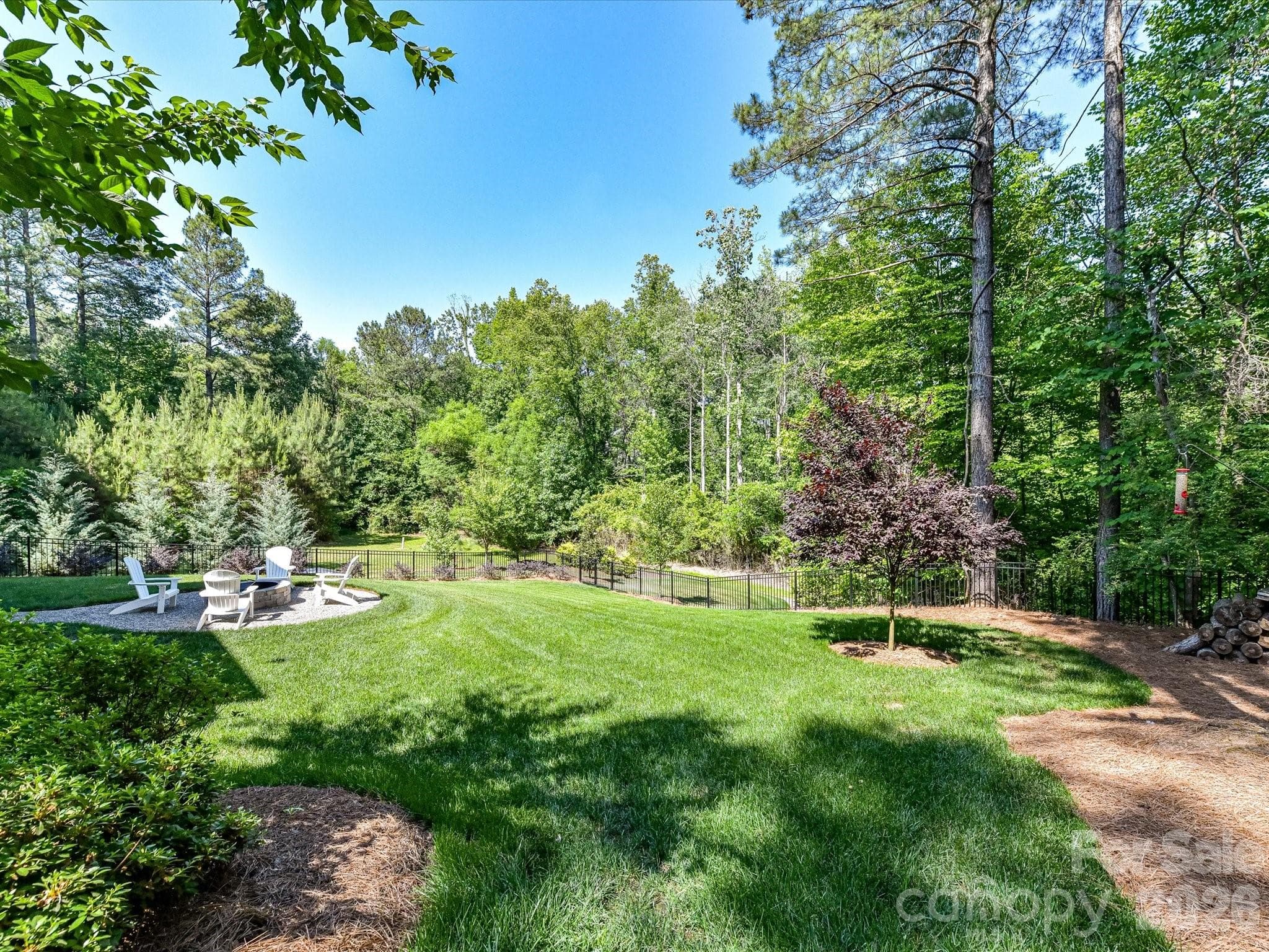Private, tree-lined and fenced backyard offers a spacious lawn, firepit gathering area, and peaceful outdoor living with plenty of room to relax or entertain. - Troutman