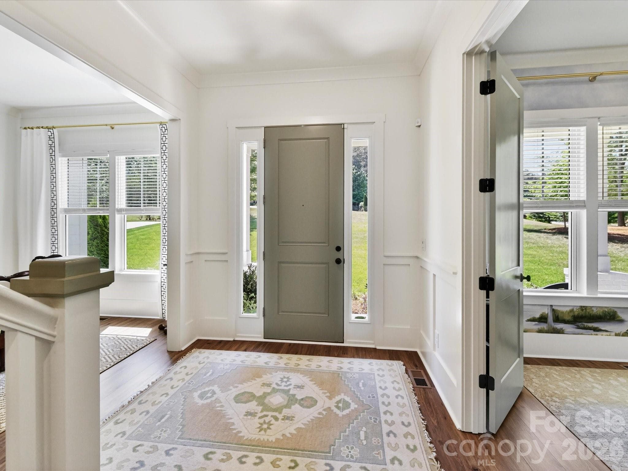 Bright and inviting entryway showcases elegant wainscoting, durable LVP flooring, and an open staircase design that creates a warm and welcoming first impression. - Troutman