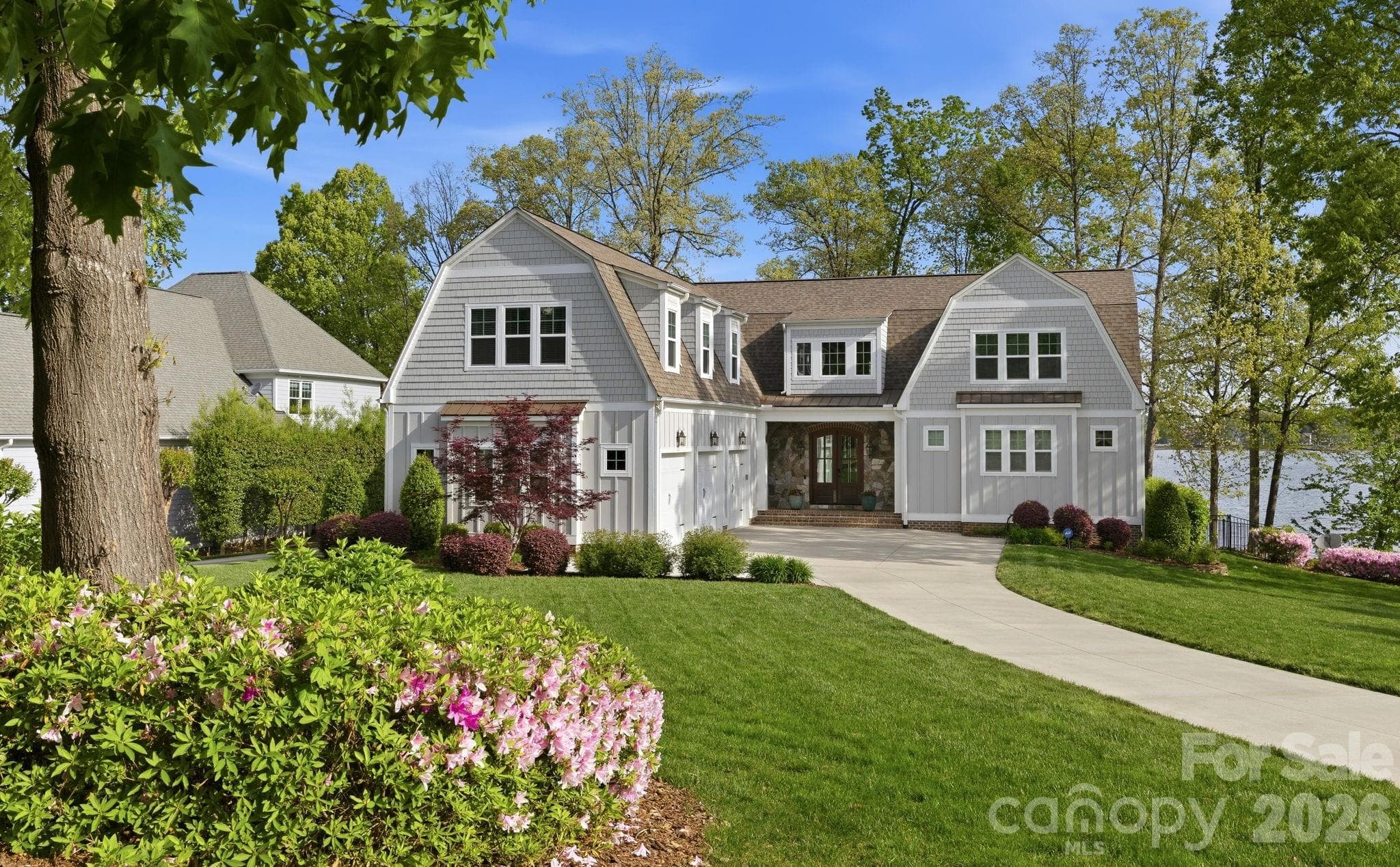 Charming waterfront home with manicured landscaping, inviting front entry, and a spacious three-car garage. - Cornelius