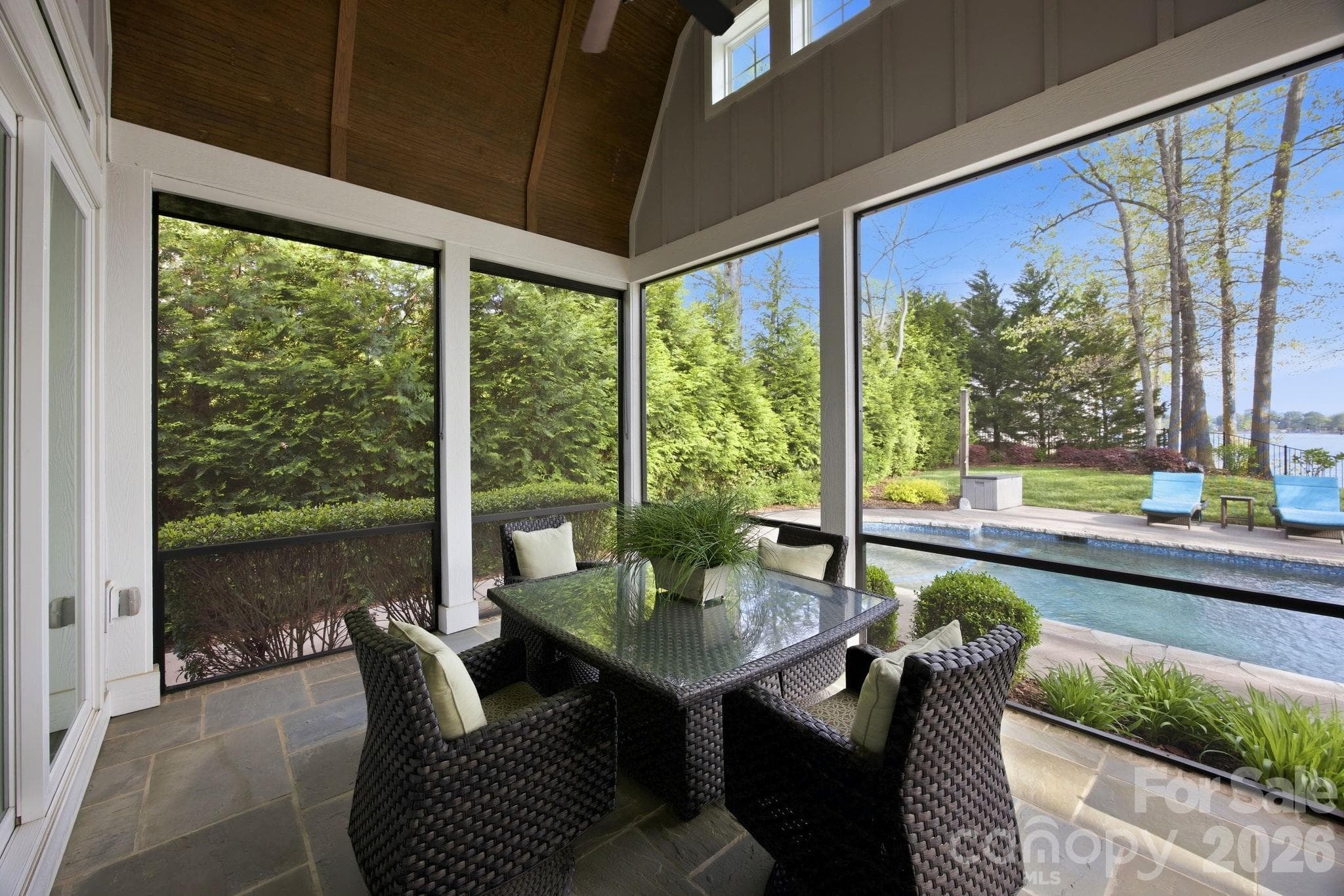 Screened porch offers a covered outdoor living space with seating and views of the pool and landscaped yard. - Cornelius