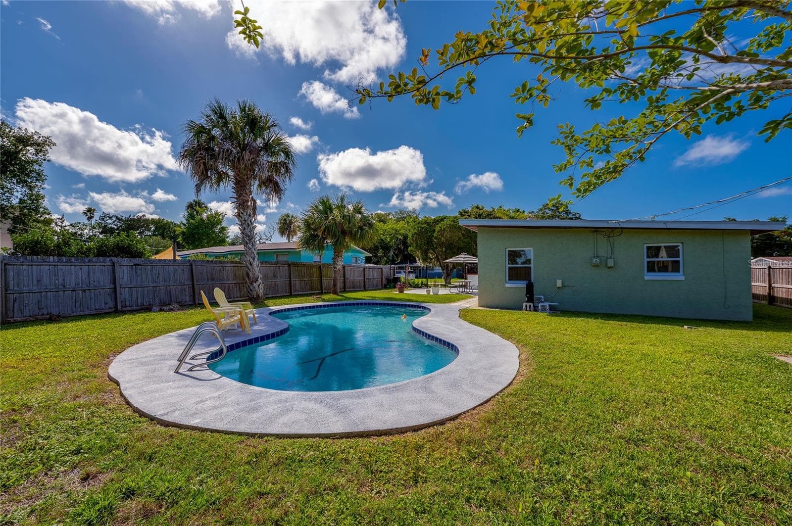 Sun-drenched outdoor oasis featuring mature palm trees and a pristine pool ideal for warm-weather relaxation. - 723 STEELE AVE, SOUTH DAYTONA