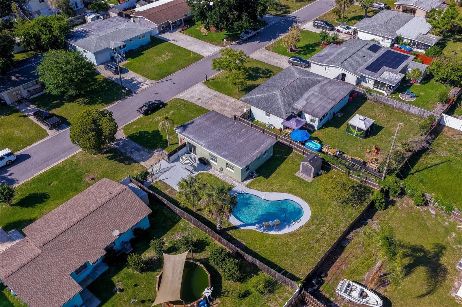 High-angle backyard aerial view capturing the home’s gated patio area, detached storage shed, privacy fencing, and refreshing pool. - 723 STEELE AVE, SOUTH DAYTONA