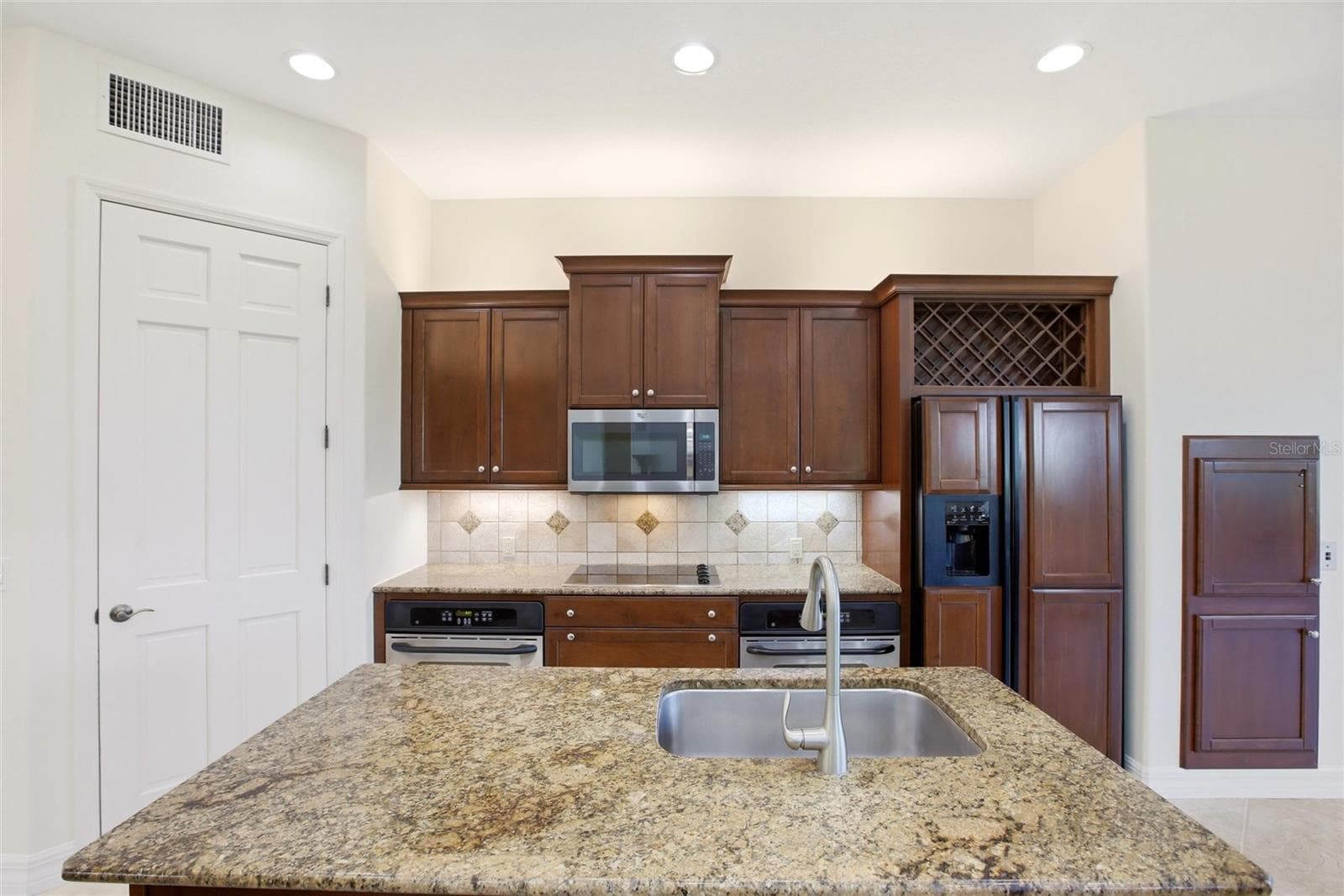 The kitchen offers an extensive breakfast bar and a comfortable casual dining area, along with generous counter space, dual sinks, double ovens, abundant cabinetry, and a spacious walk-in pantry. - 8417 LONE EAGLE WAY, SARASOTA