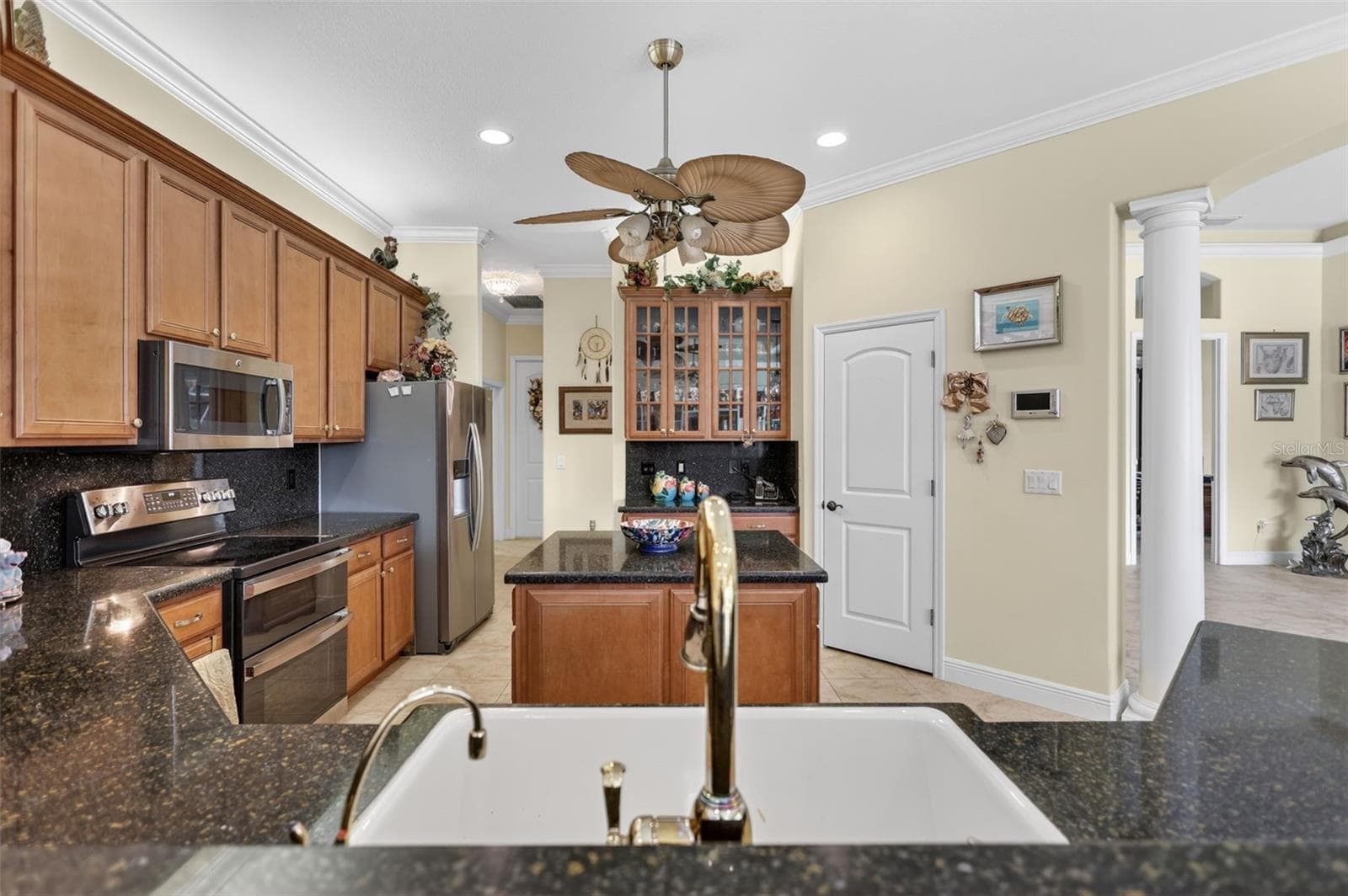 Open-concept family living spaces showcase tray ceilings, crown molding, custom built-in shelving, and expansive views of the pool and surrounding acreage. - 1210 408TH CT E, MYAKKA CITY