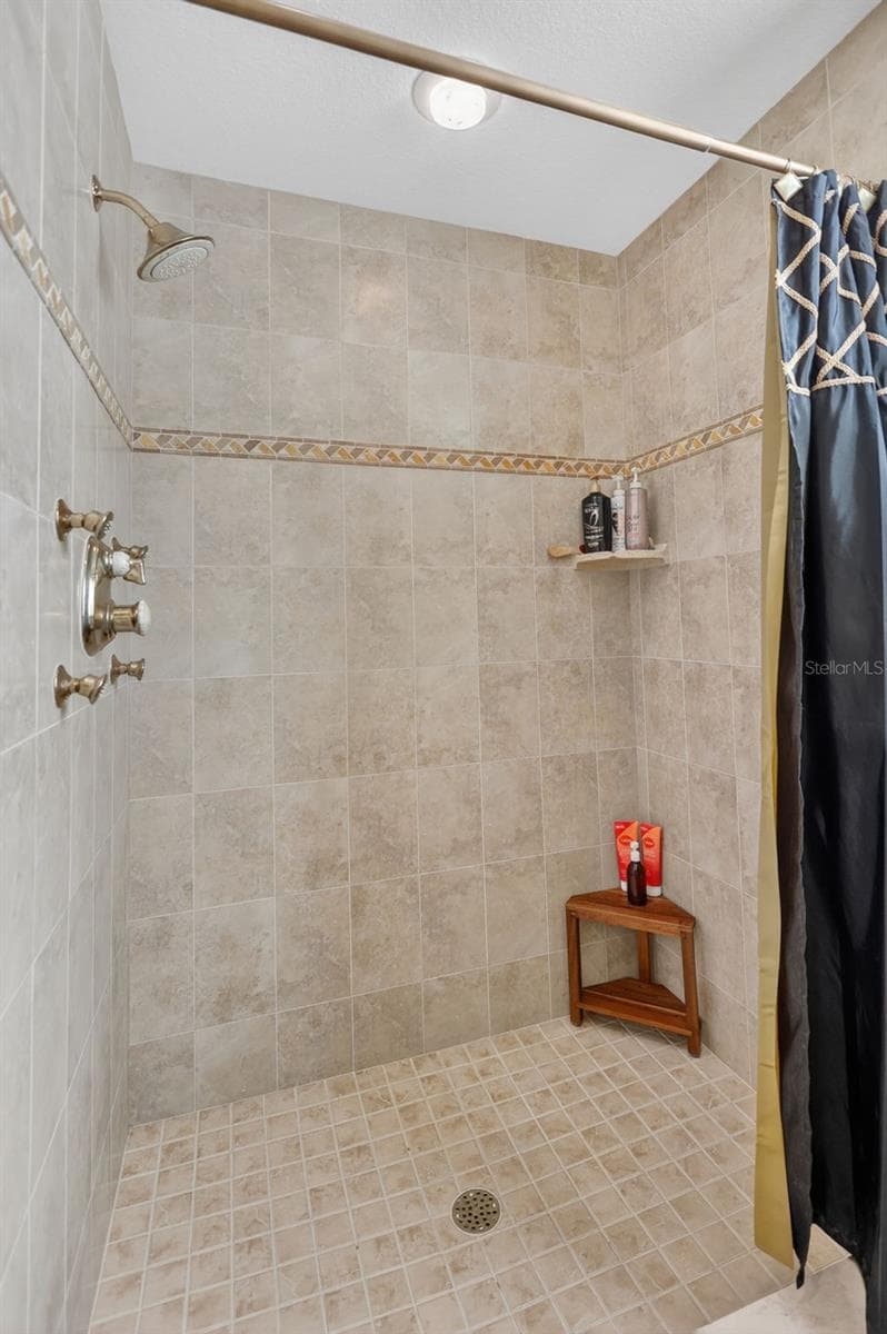 The spacious walk-in shower features floor-to-ceiling tile, decorative accents, and a clean, timeless design. - 1210 408TH CT E, MYAKKA CITY