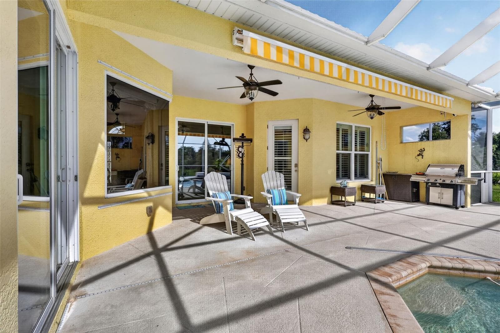 The expansive covered lanai creates the perfect setting for outdoor entertaining, complete with ample seating areas, ceiling fans, and convenient access to the outdoor kitchen. - 1210 408TH CT E, MYAKKA CITY