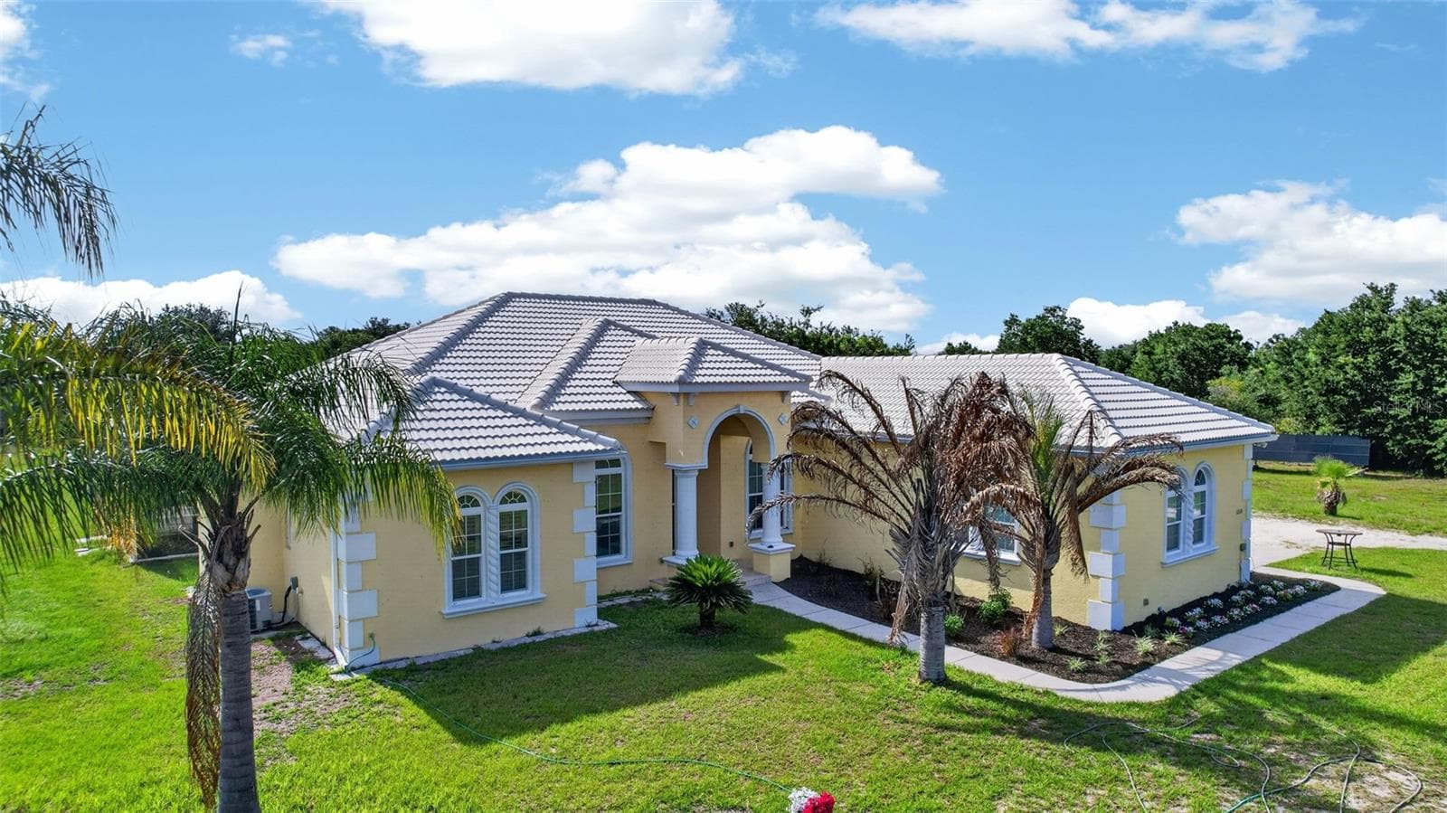 Architectural details, mature palms, and a grand entryway contribute to the home's impressive presence and timeless design. - 1210 408TH CT E, MYAKKA CITY