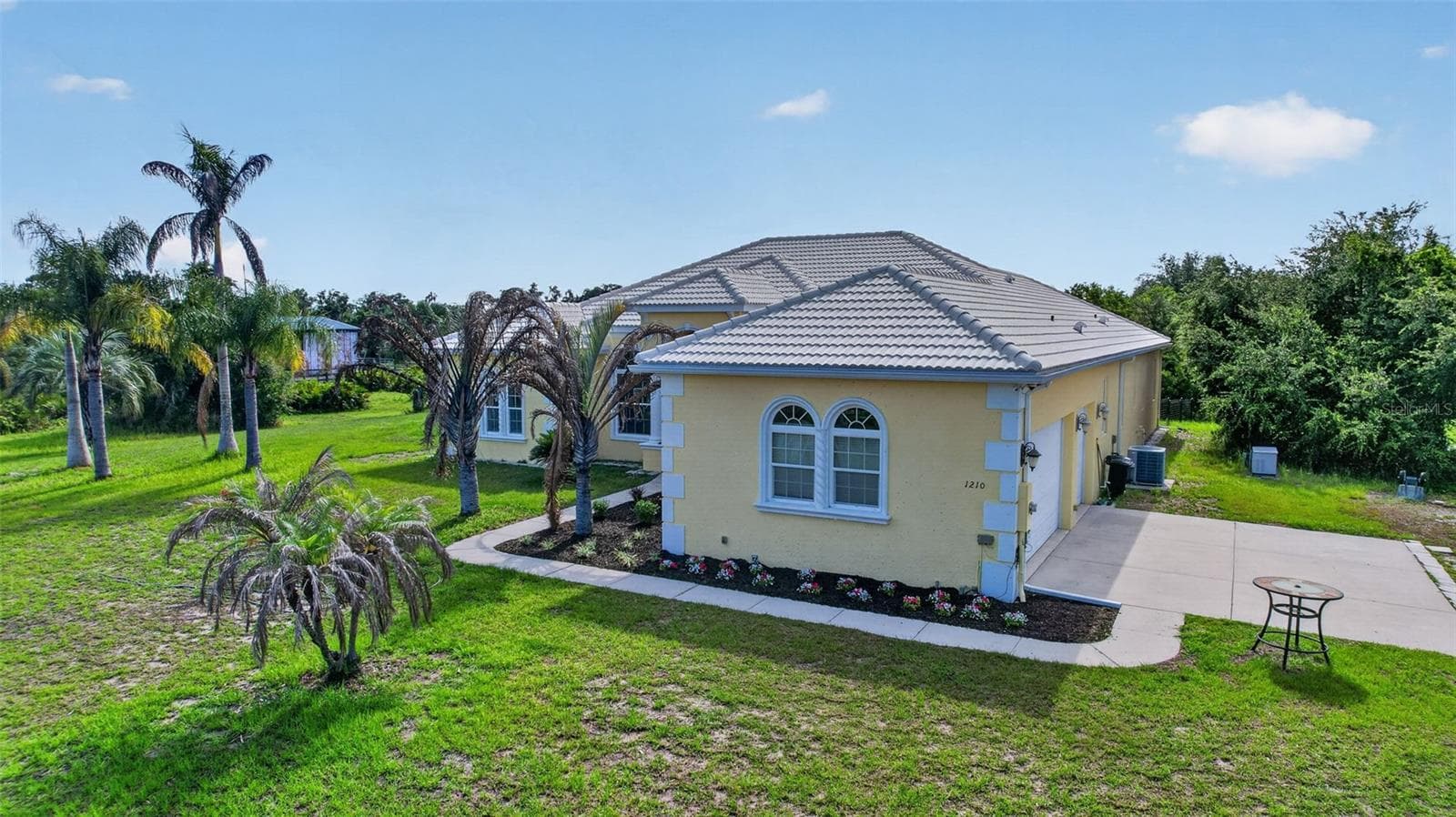 Set back from the road and framed by mature palms and a private pond, the residence enjoys both privacy and picturesque surroundings - 1210 408TH CT E, MYAKKA CITY