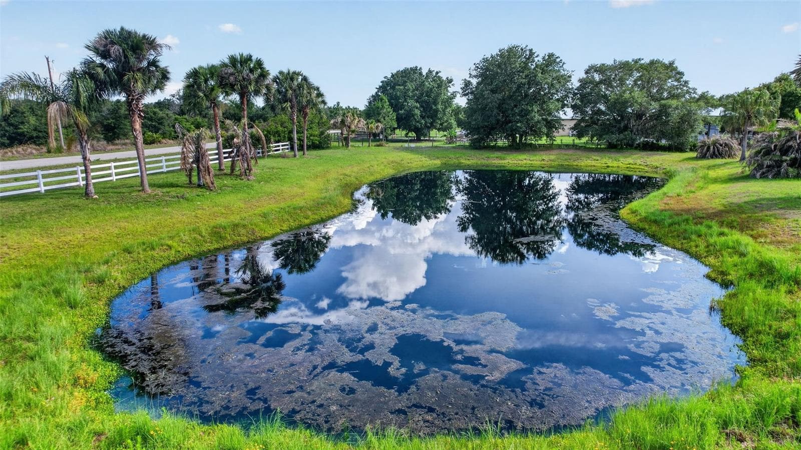 A scenic pond and mature landscaping contribute to the estate's peaceful atmosphere and park-like setting - 1210 408TH CT E, MYAKKA CITY