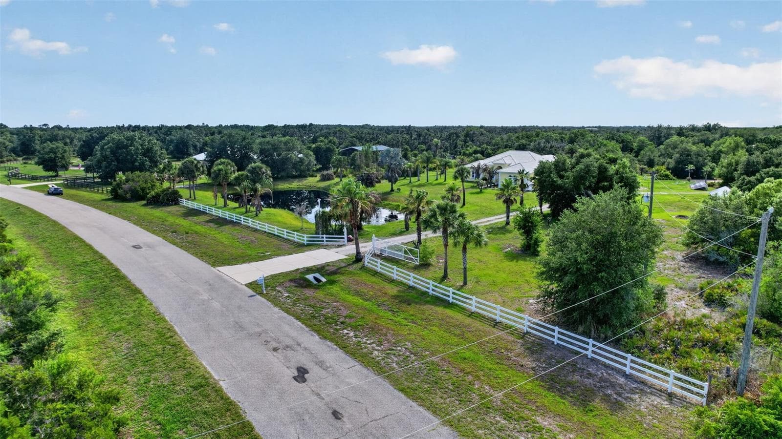 An expansive aerial view captures the property's impressive acreage, private pond, mature landscaping, and the surrounding rural landscape that defines this exceptional estate. - 1210 408TH CT E, MYAKKA CITY