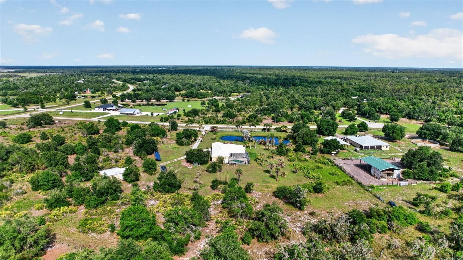 From this aerial perspective, the thoughtful placement of the home, pool, outbuildings, and solar array creates a truly self-contained private retreat. - 1210 408TH CT E, MYAKKA CITY