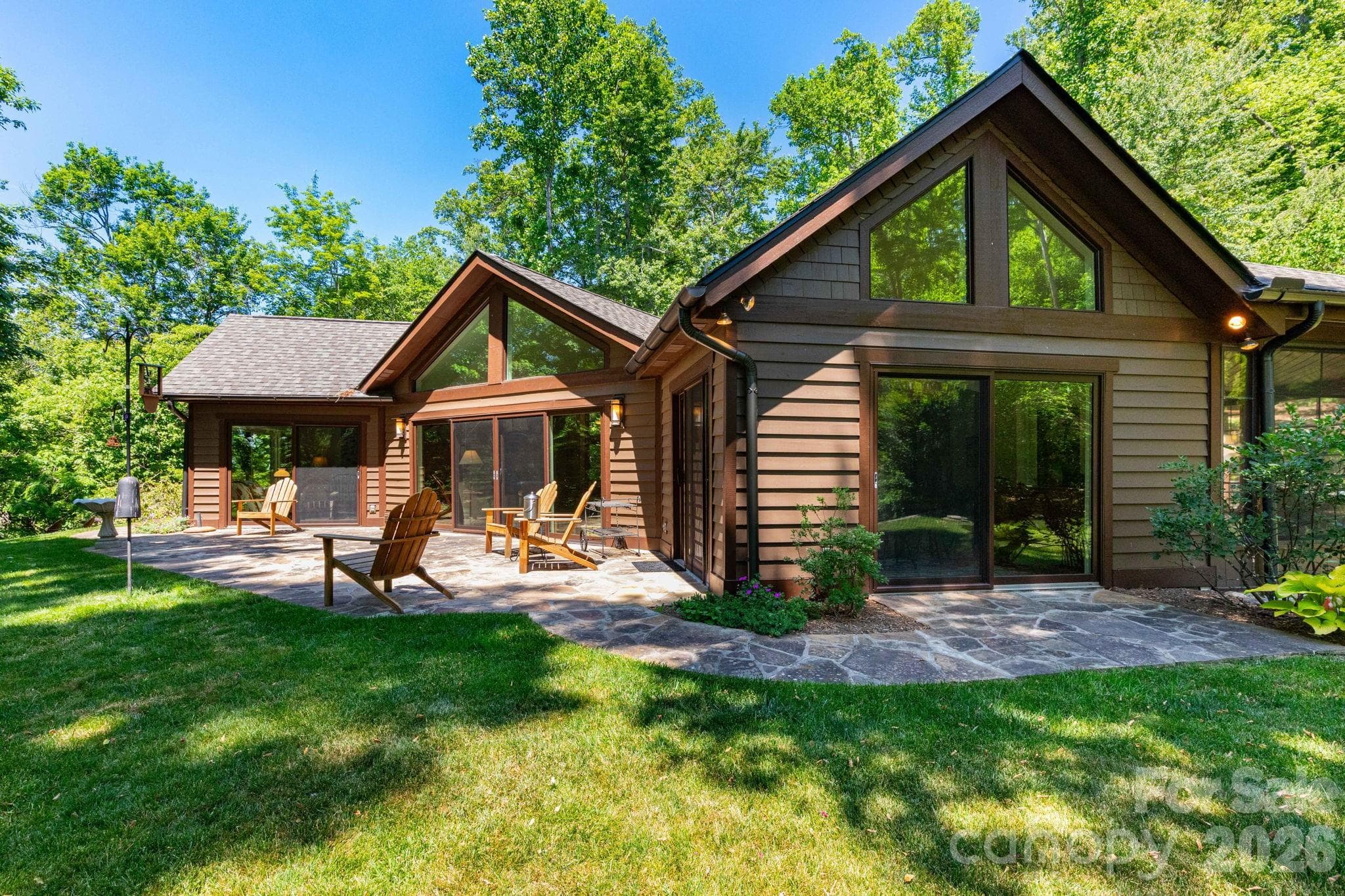 Expansive outdoor entertaining spaces with stone patios, level lawn areas, and floor-to-ceiling windows that seamlessly connect indoor and outdoor living. - 29 Gardner Drive, Asheville