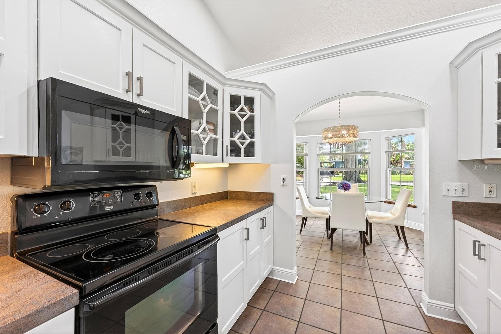 The Kitchen showcases BEAUTIFULLY UPDATED SOLID WOOD WHITE CABINETRY, including select glass-front display cabinets. - 2706 HARGILL DR, ORLANDO