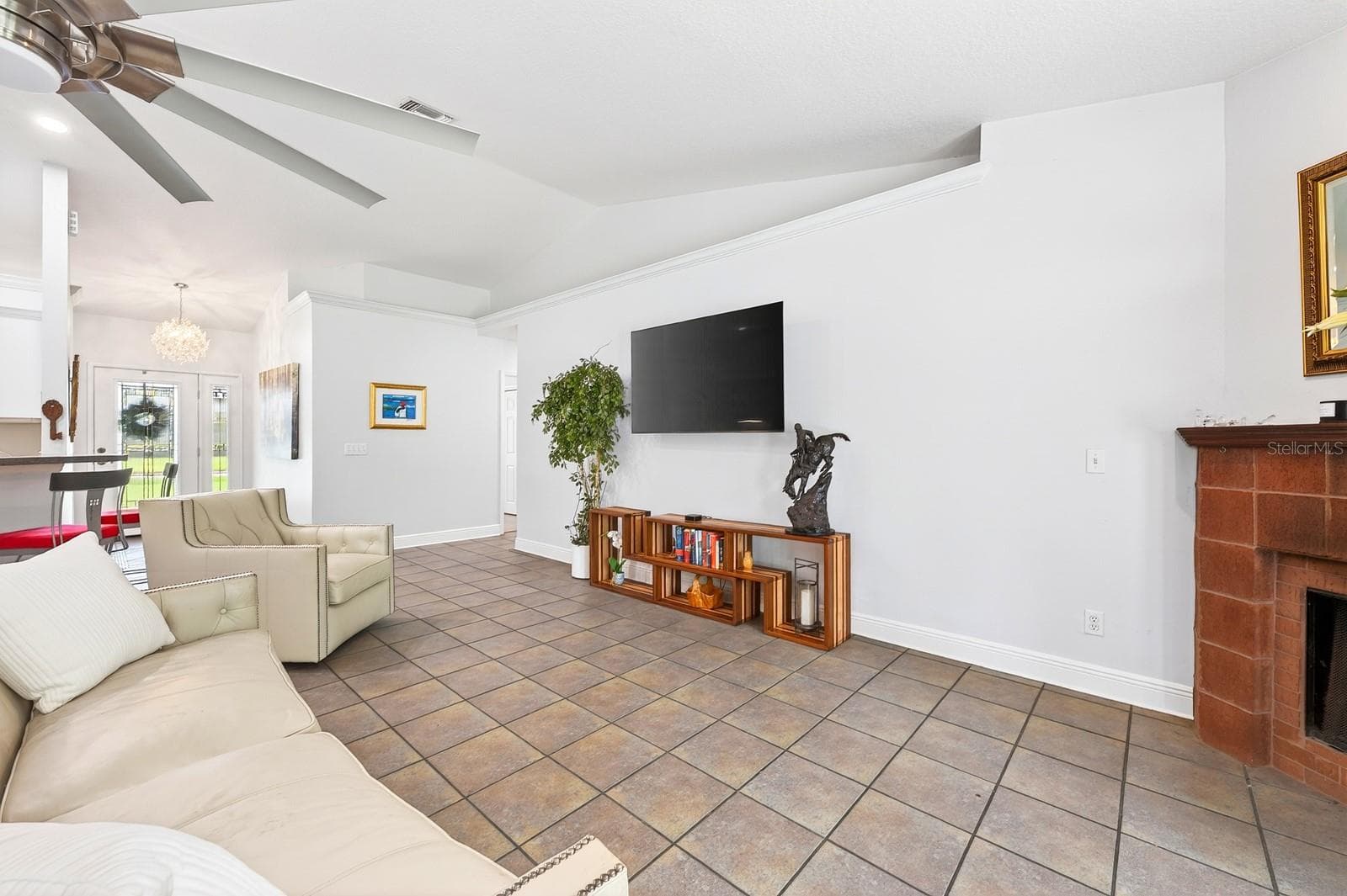 A spacious Family Room impresses with soaring vaulted ceilings, a STYLISH SLINGER CEILING FAN (2021), and a beautiful MASONRY WOOD-BURNING FIREPLACE. - 2706 HARGILL DR, ORLANDO