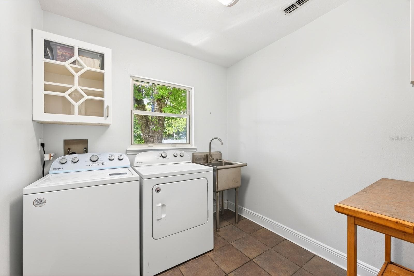 The spacious Laundry Room is thoughtfully equipped with a STAINLESS STEEL UTILITY TUB, cabinetry, folding table, and included washer and dryer. - 2706 HARGILL DR, ORLANDO