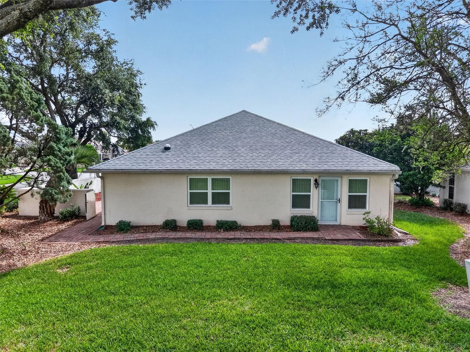 Rear view of the home situated on a corner lot with lush green lawn maintained by the community. - 17808 SE 115TH CT, SUMMERFIELD