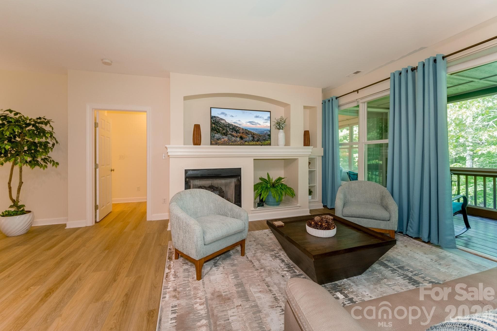 Living Room with Fireplace & Screened Porch Access – Spacious living area featuring a cozy gas fireplace, built-in architectural details, and seamless access to the screened porch overlooking peaceful wooded surroundings. - 99 Ridgetop Circle, Brevard