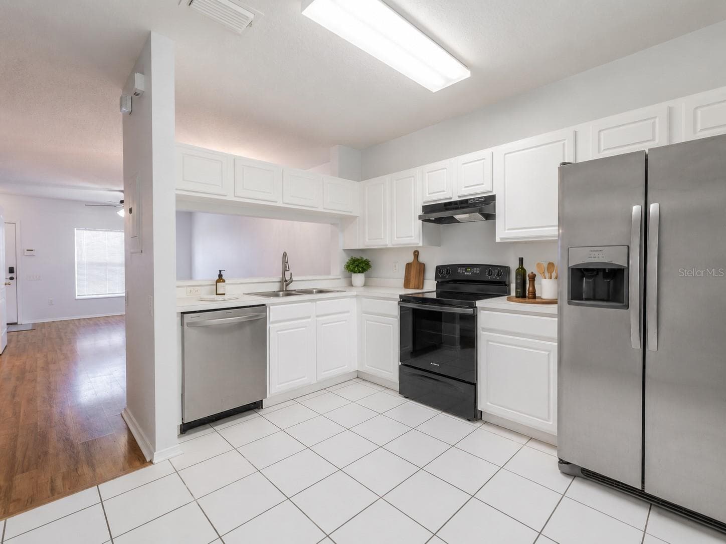 Kitchen features ceramic tile flooring, stainless steel appliances including a French door refrigerator with ice maker and water dispenser, an electric range and sliding glass door to the private screened in patio. - 2432 LAKE WOODBERRY CIR, BRANDON