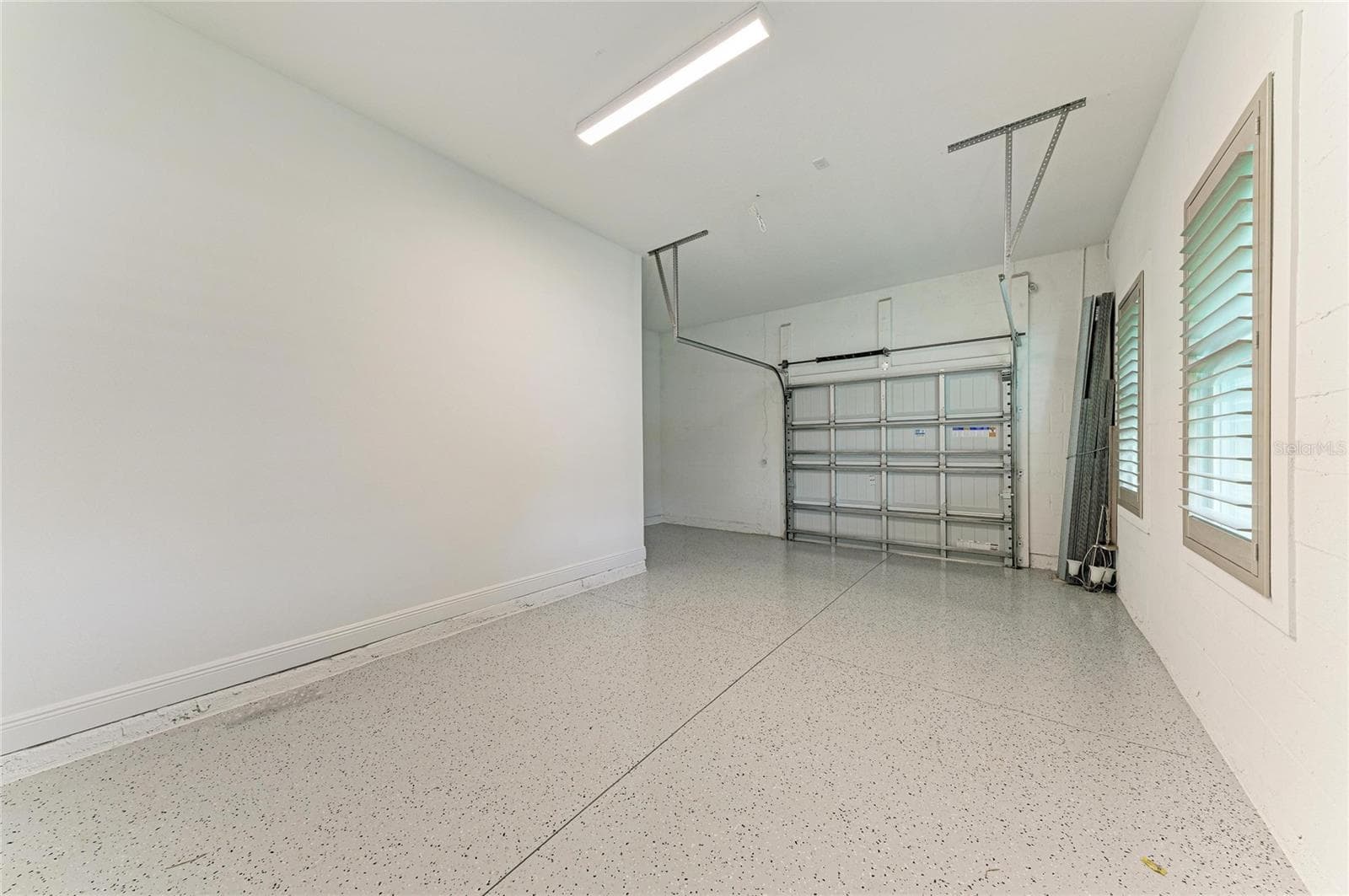 Spacious garage featuring epoxy-coated flooring and ample storage - 17725 ROOST PL, LAKEWOOD RANCH