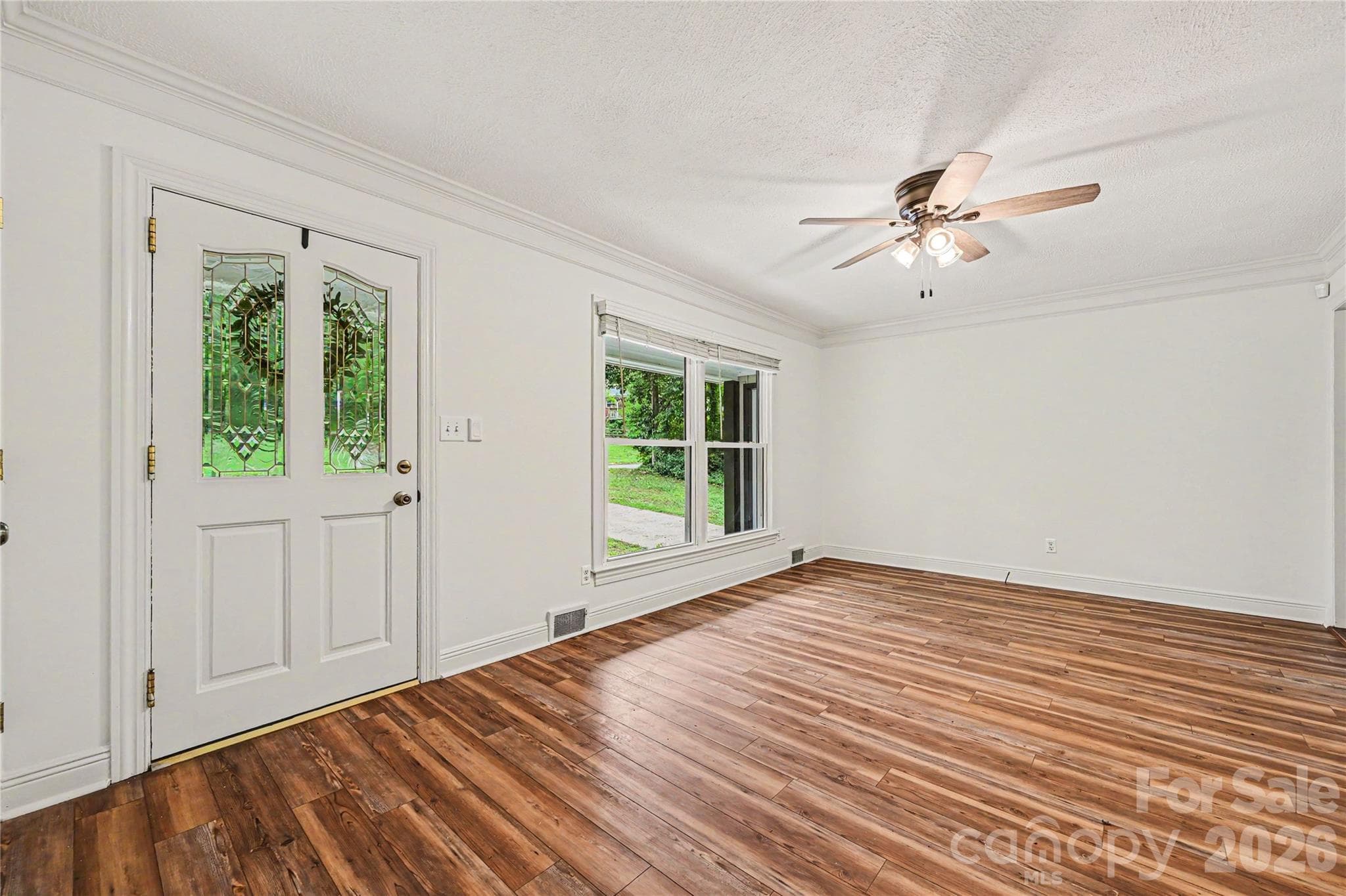 Bright and spacious living room featuring large front windows, crown molding, and durable LVP flooring. - Concord