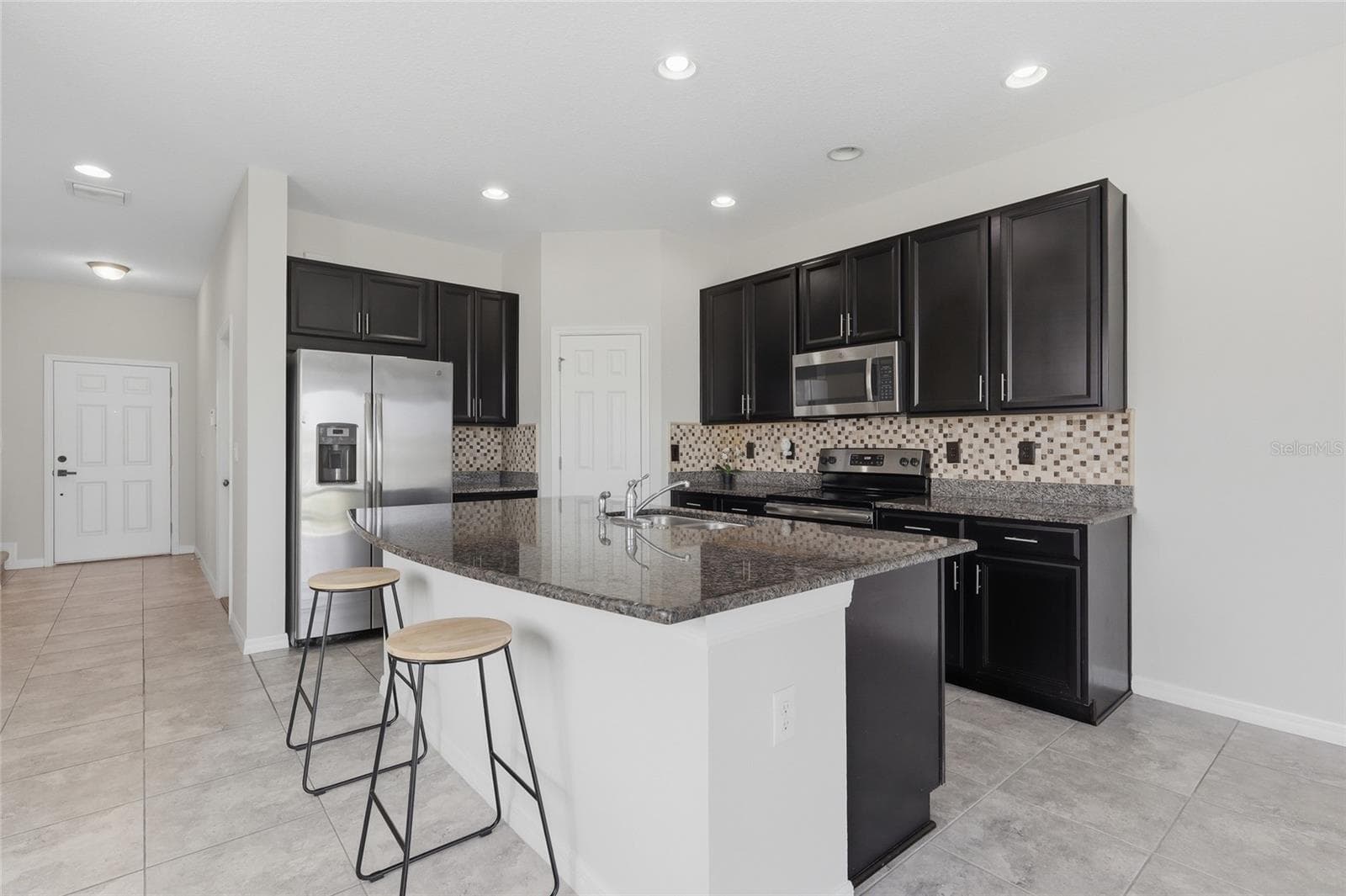 Modern kitchen featuring dark wood cabinetry, granite counters, and a spacious center island - 7005 GRAND ELM DR, RIVERVIEW