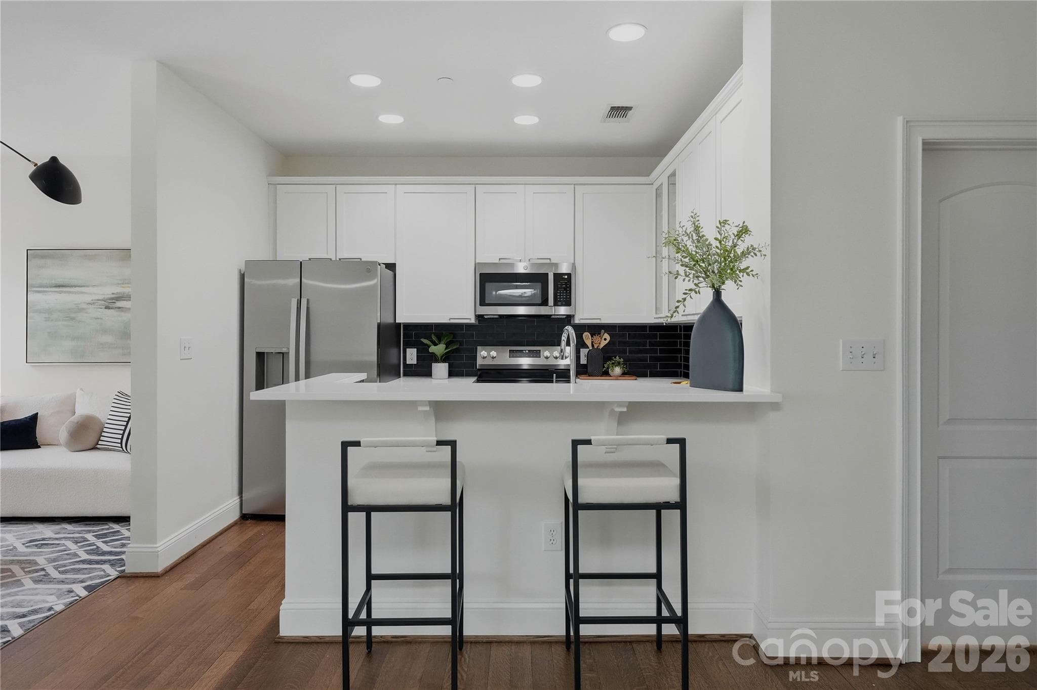Pull up a seat at the peninsula breakfast bar with quartz countertops and modern bar stools making it the perfect spot for morning coffee or entertaining guests. - Charlotte