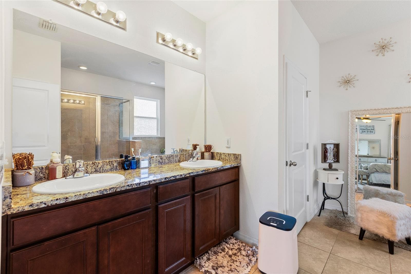 The luxurious primary bathroom includes a double-sink granite vanity, soaking garden tub, separate walk-in shower, and ample storage space, creating a spa-like atmosphere for everyday comfort and relaxation. - 5025 JACKEL CHASE DR, WIMAUMA