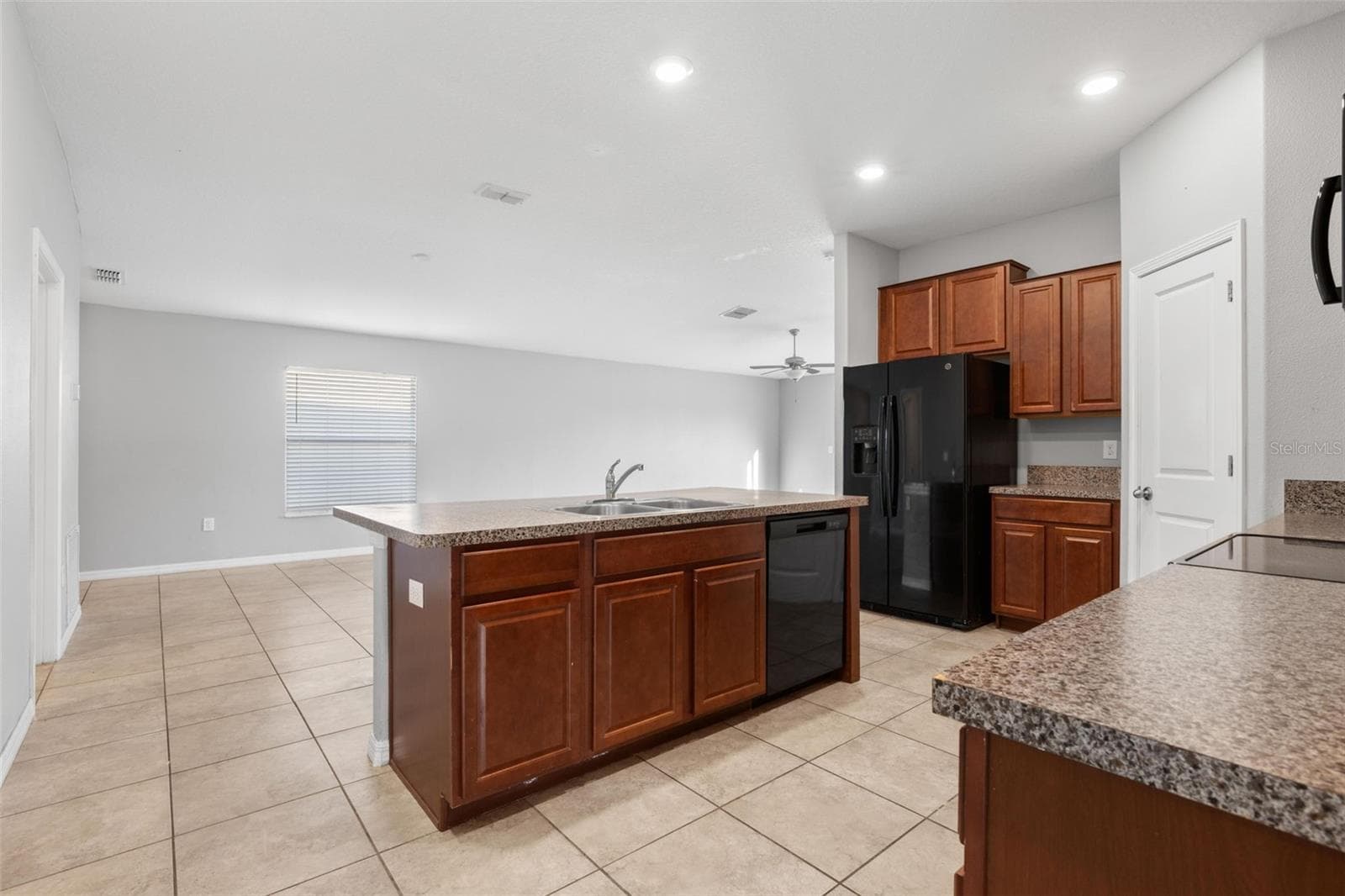 Kitchen with a double-basin stainless steel sink, granite countertops, black appliances, recessed lighting, tile flooring, and a peninsula with breakfast bar seating and cabinet storage. - 6810 TRENT CREEK DR, SUN CITY CENTER
