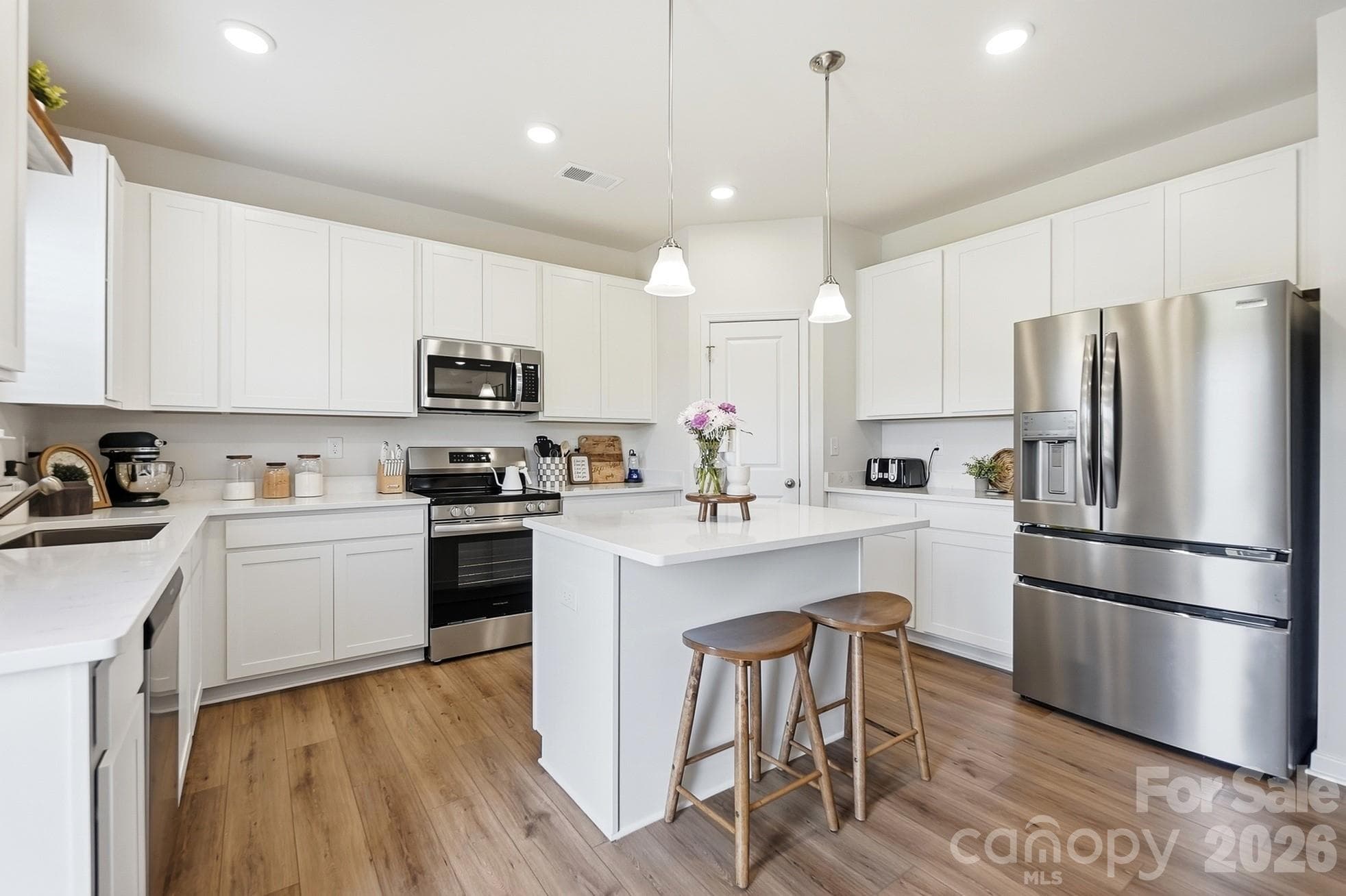 Bright kitchen featuring white cabinetry, center island, and stainless appliances. - 6023 Busch Way, Midland