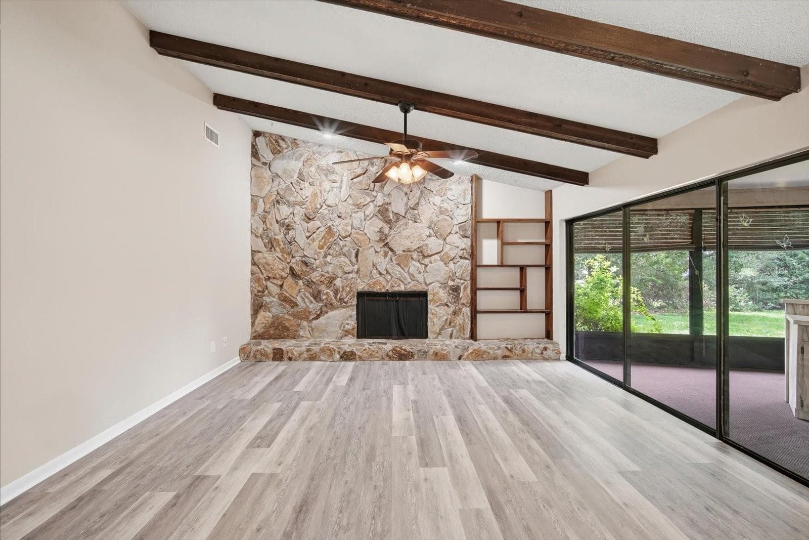 Impressive family room with soaring ceilings with stone fireplace, beams and triple sliding glass doors - 1405 LAUREL CT, PLANT CITY