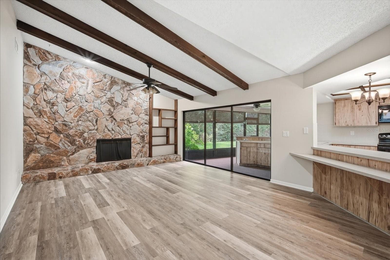 Impressive family room with soaring ceilings with stone fireplace, beams and triple sliding glass doors - 1405 LAUREL CT, PLANT CITY