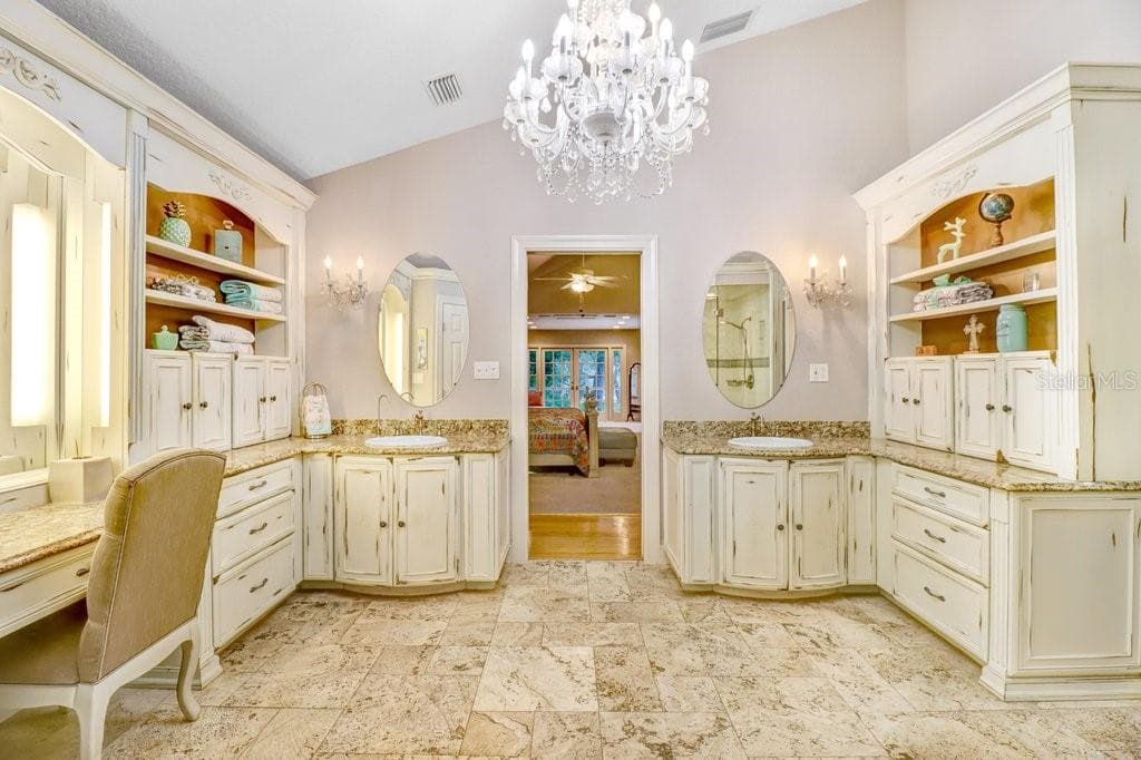 Vaulted ceilings in master bathroom with chandelier and his and her sink areas ample cabinetry for storage. - 1976 DUNLOE CIR, DUNEDIN