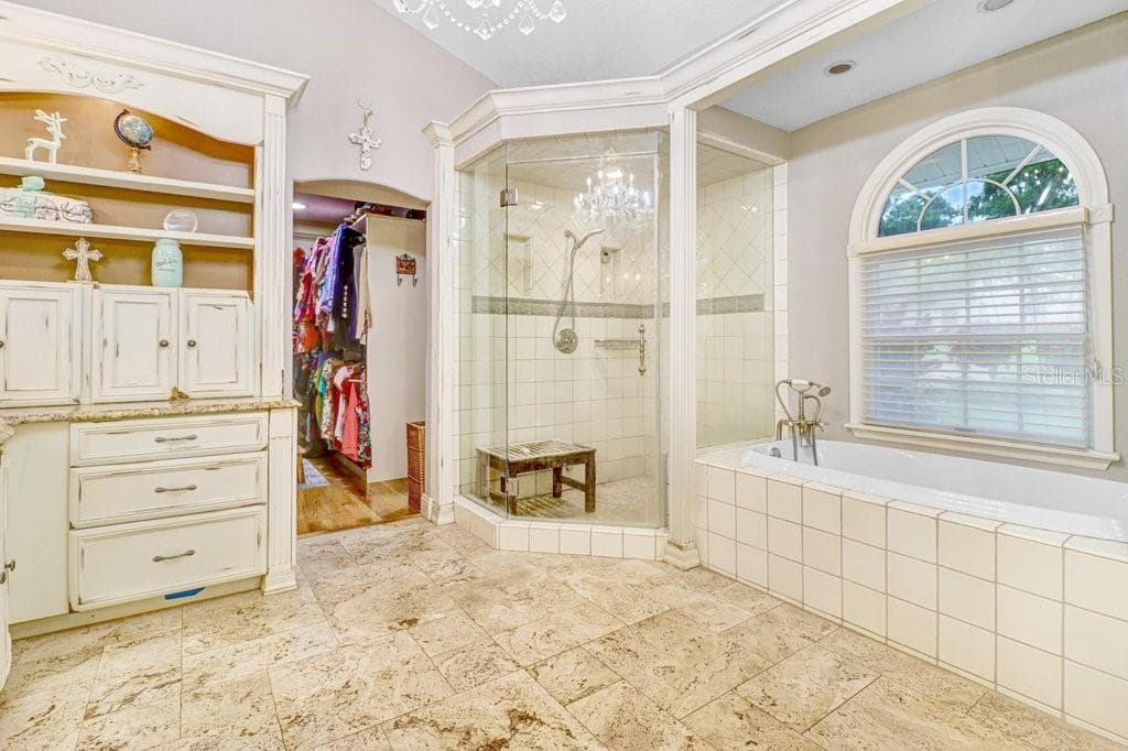 Large walk in steam shower with custom tile and shampoo nooks. Doorway to master bedroom closet. - 1976 DUNLOE CIR, DUNEDIN