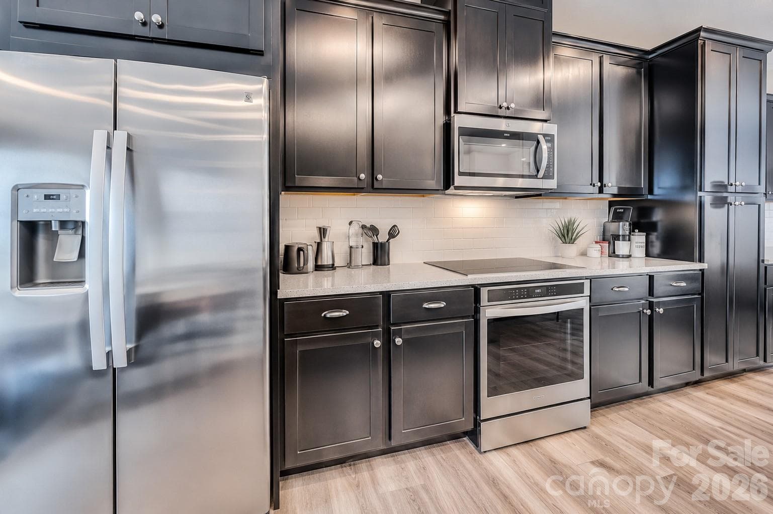 The modern kitchen showcases stainless steel appliances, abundant cabinetry, sleek quartz countertops, a subway tile backsplash, and ample prep space, creating the perfect blend of style and functionality. - 3019 Jolene Court, Charlotte