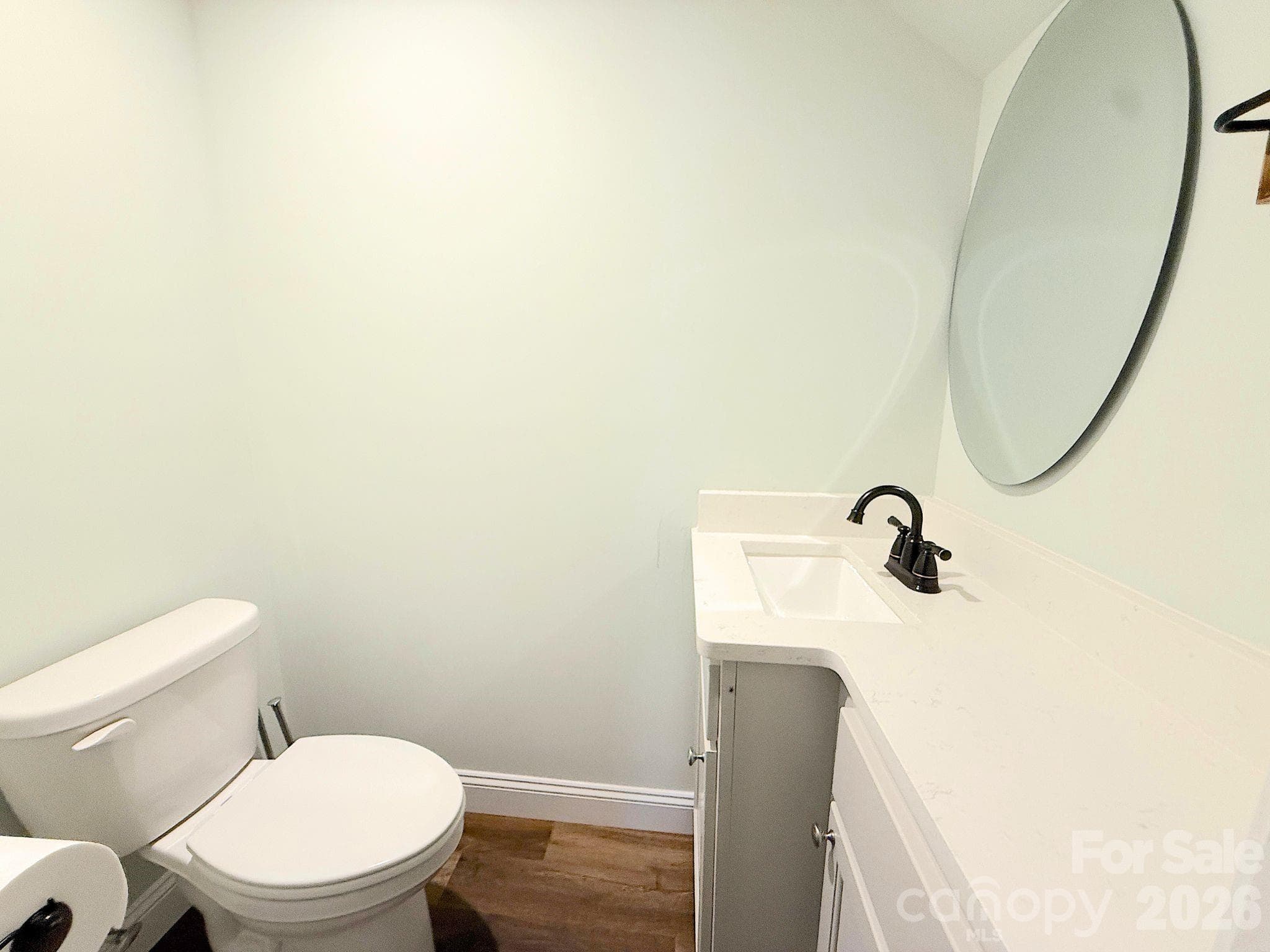 Powder Room – Convenient main-level half bath featuring a modern vanity with solid-surface countertop, updated fixtures, and a contemporary round mirror. - Chester