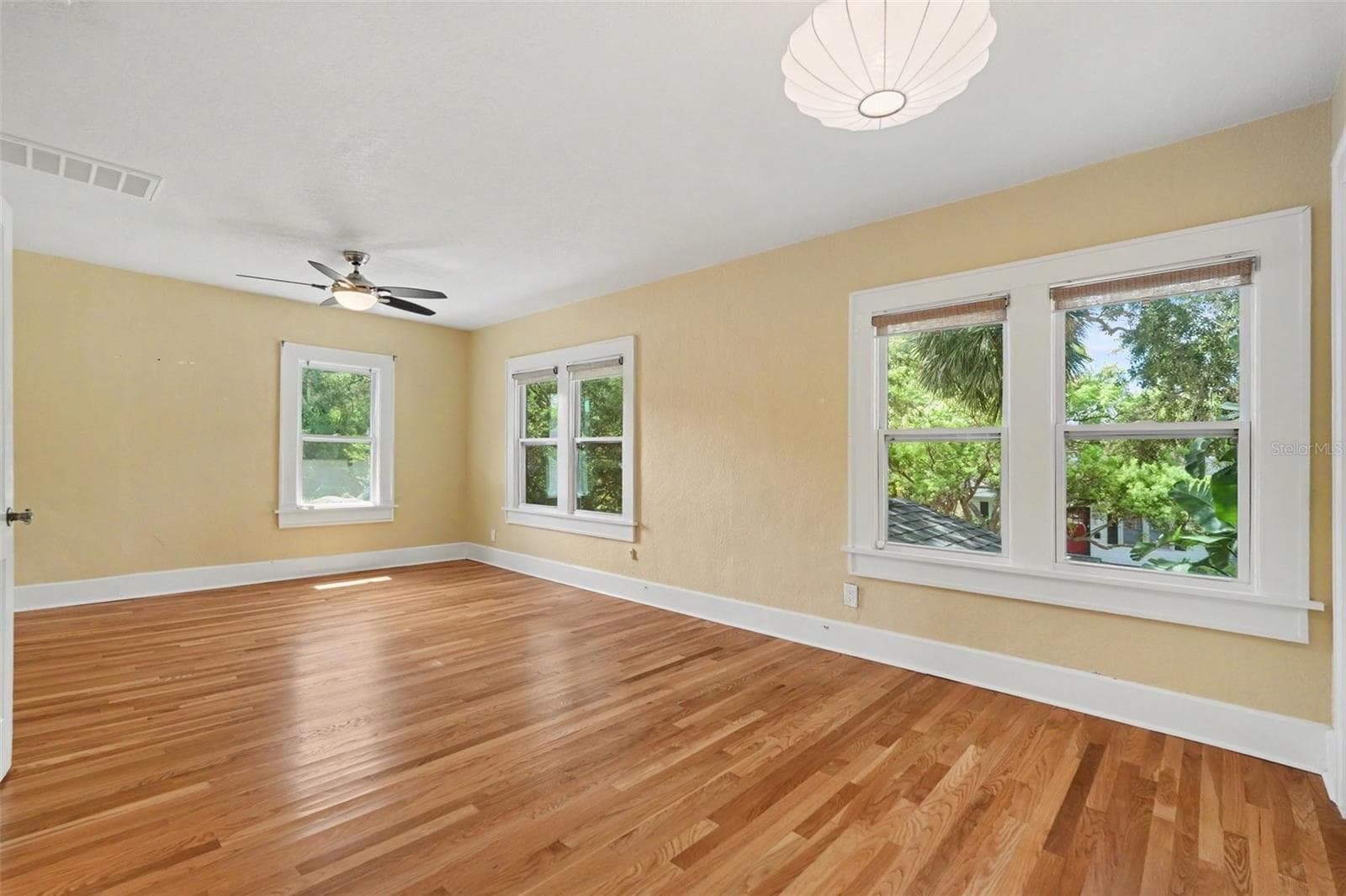 Multiple windows frame leafy neighborhood views, giving the primary bedroom a bright and peaceful feel. - 857 21ST AVE N, ST PETERSBURG
