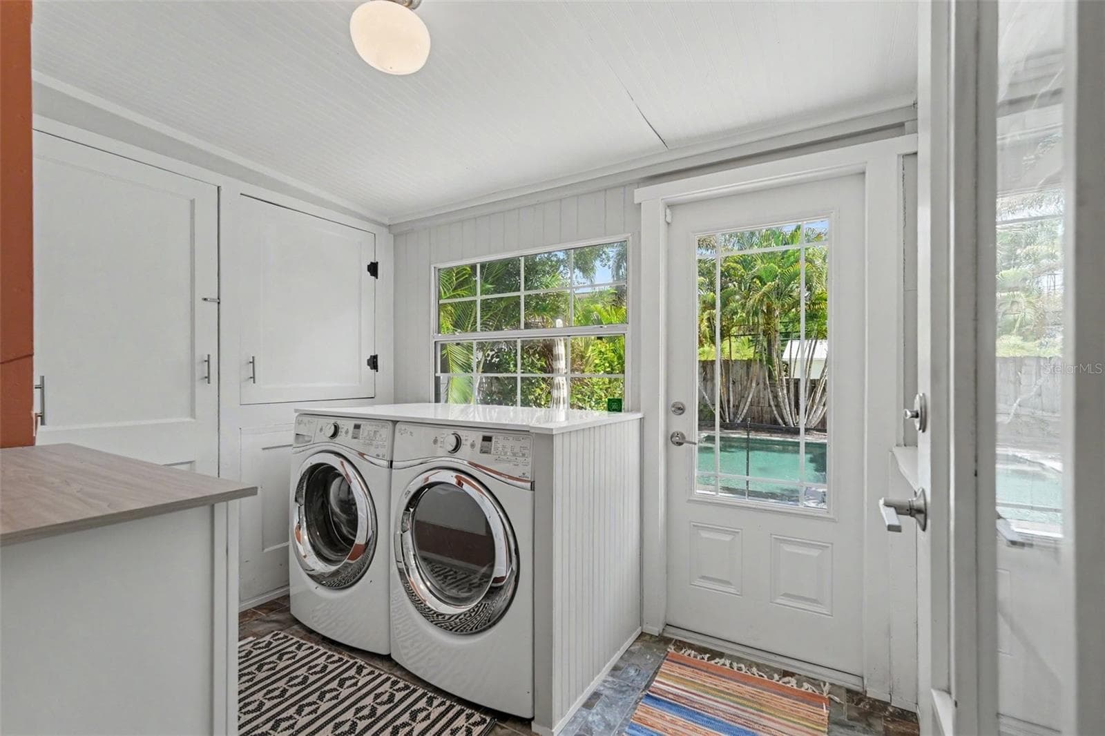 A bright and functional laundry room offers generous built-in storage, full-size washer and dryer space, and direct access to the pool and backyard. - 857 21ST AVE N, ST PETERSBURG