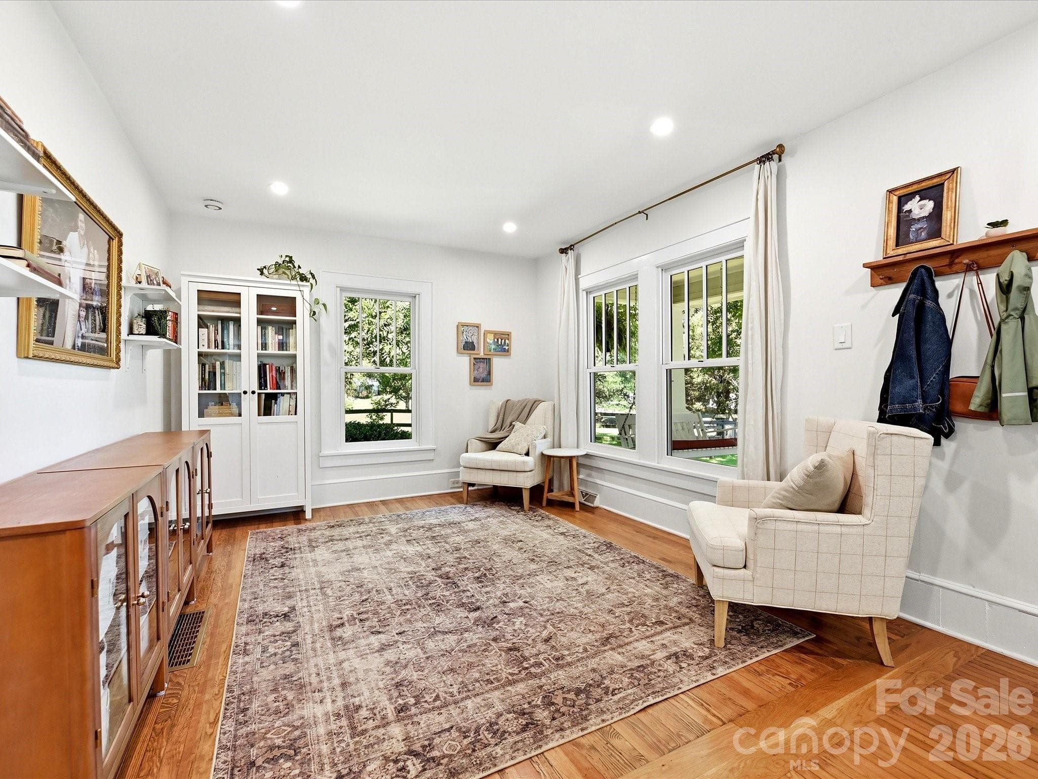 Enjoy an open, light-filled living area with charming architectural details, gleaming hardwood floors, and views of the welcoming front porch. - 3514 Kelly Road, Charlotte