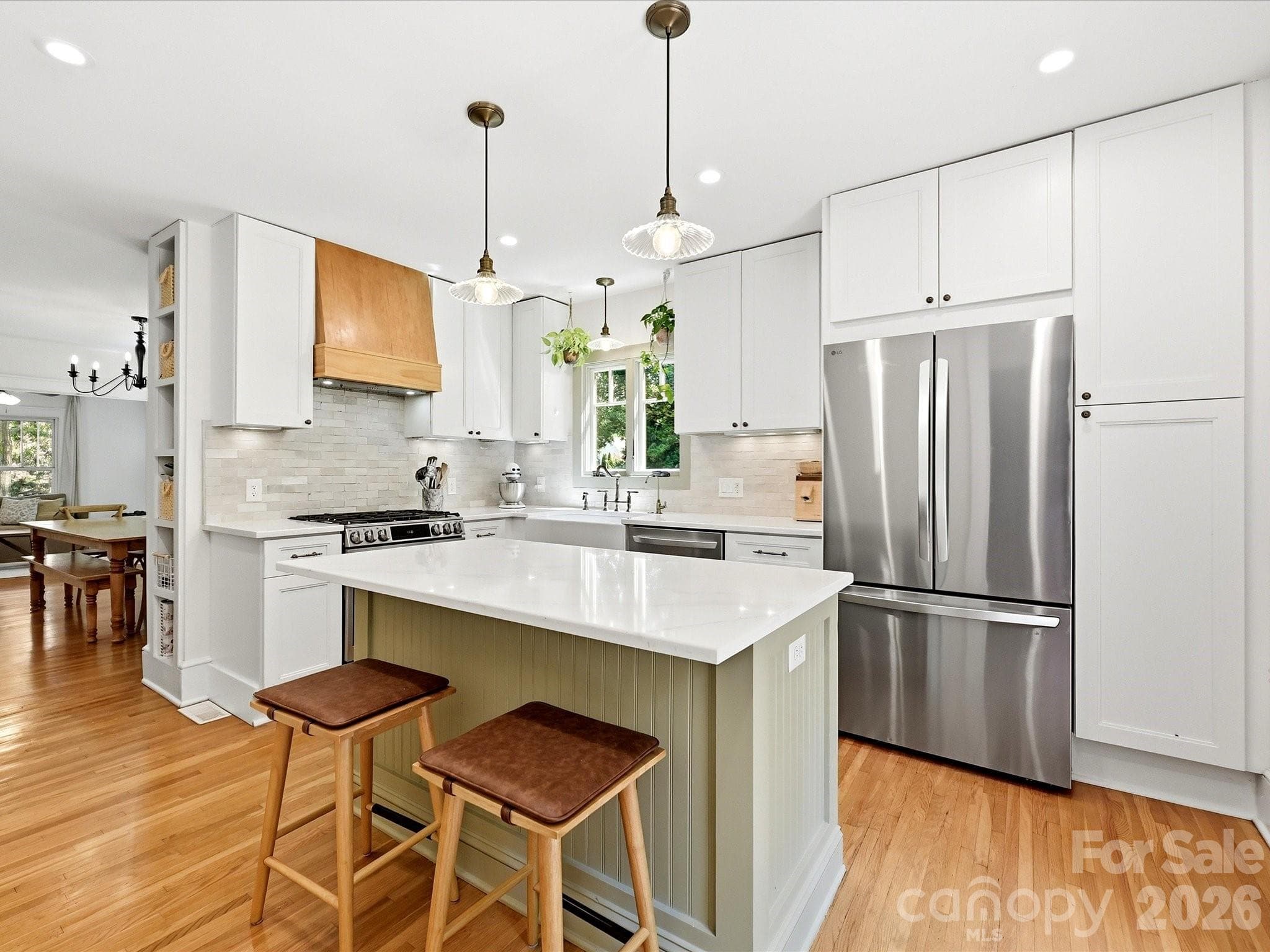 The beautifully updated kitchen features quartz countertops, a farmhouse sink, stainless steel appliances, a center island with seating, and direct access to the outdoor living space. - 3514 Kelly Road, Charlotte