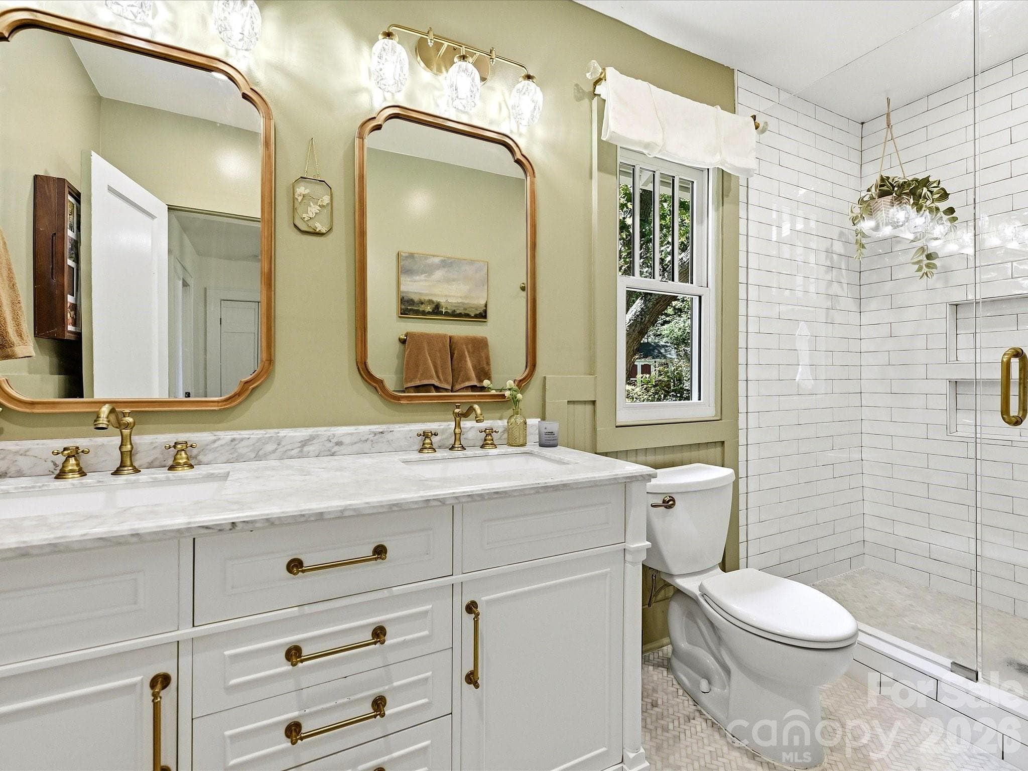 Beautifully renovated, this spa-inspired bathroom features a marble-topped dual vanity, designer fixtures, and a stunning walk-in tiled shower with frameless glass enclosure. - 3514 Kelly Road, Charlotte