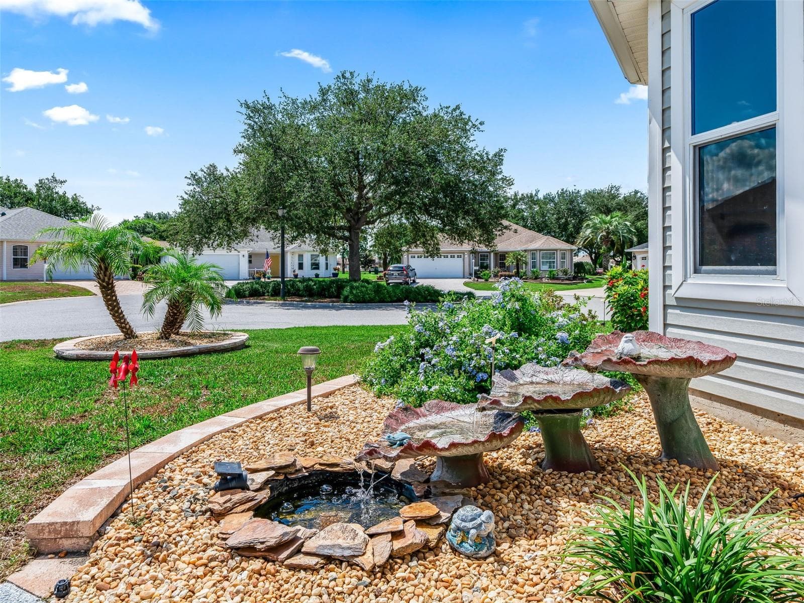 Charming landscaped garden area with mature plantings, decorative stone accents, and a peaceful water feature creates an inviting outdoor focal point. - 17946 SE 87TH MELROSE CT, THE VILLAGES