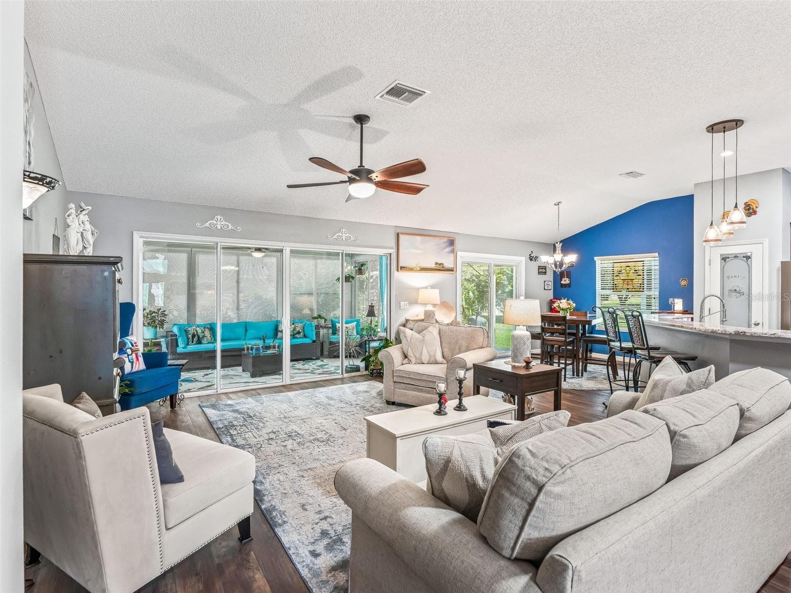 Expansive living room offers comfortable seating space, a vaulted ceiling, ceiling fan, and abundant natural light from the rear windows and glass doors. - 17946 SE 87TH MELROSE CT, THE VILLAGES