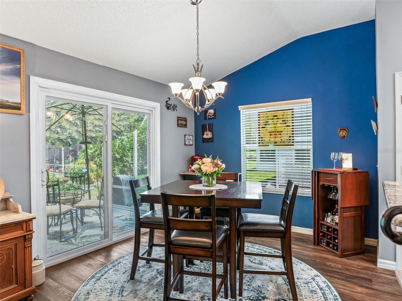 A cheerful dining space features a bold accent wall, chandelier, and UPGRADED sliding glass doors that bring in natural light and provide convenient outdoor access. - 17946 SE 87TH MELROSE CT, THE VILLAGES