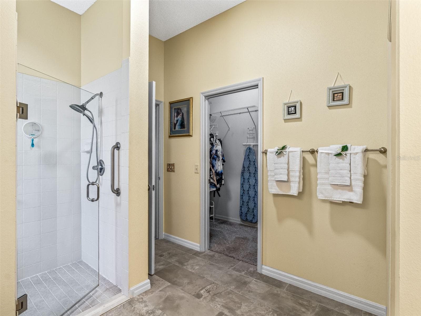 The primary bath includes a walk-in shower with glass enclosure, convenient wall-mounted fixtures, and direct access to the adjoining walk-in closet. - 17946 SE 87TH MELROSE CT, THE VILLAGES