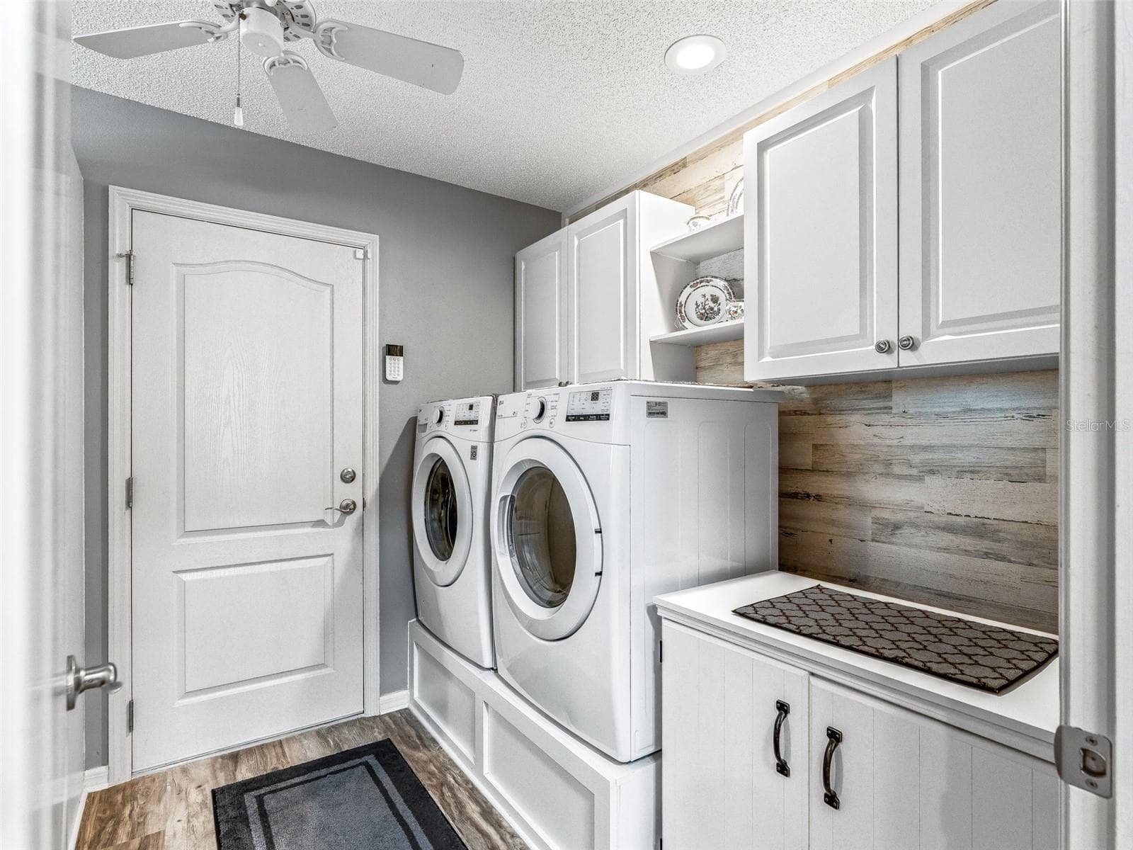 Well-equipped interior laundry room features a side-by-side washer and dryer, abundant cabinetry, a utility sink, and generous counter space for folding and storage. - 17946 SE 87TH MELROSE CT, THE VILLAGES