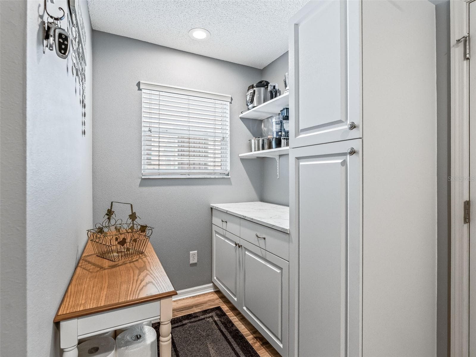 Additional built-in cabinetry, open shelving, and a convenient bench provide excellent organization and functional workspace within the laundry room. - 17946 SE 87TH MELROSE CT, THE VILLAGES