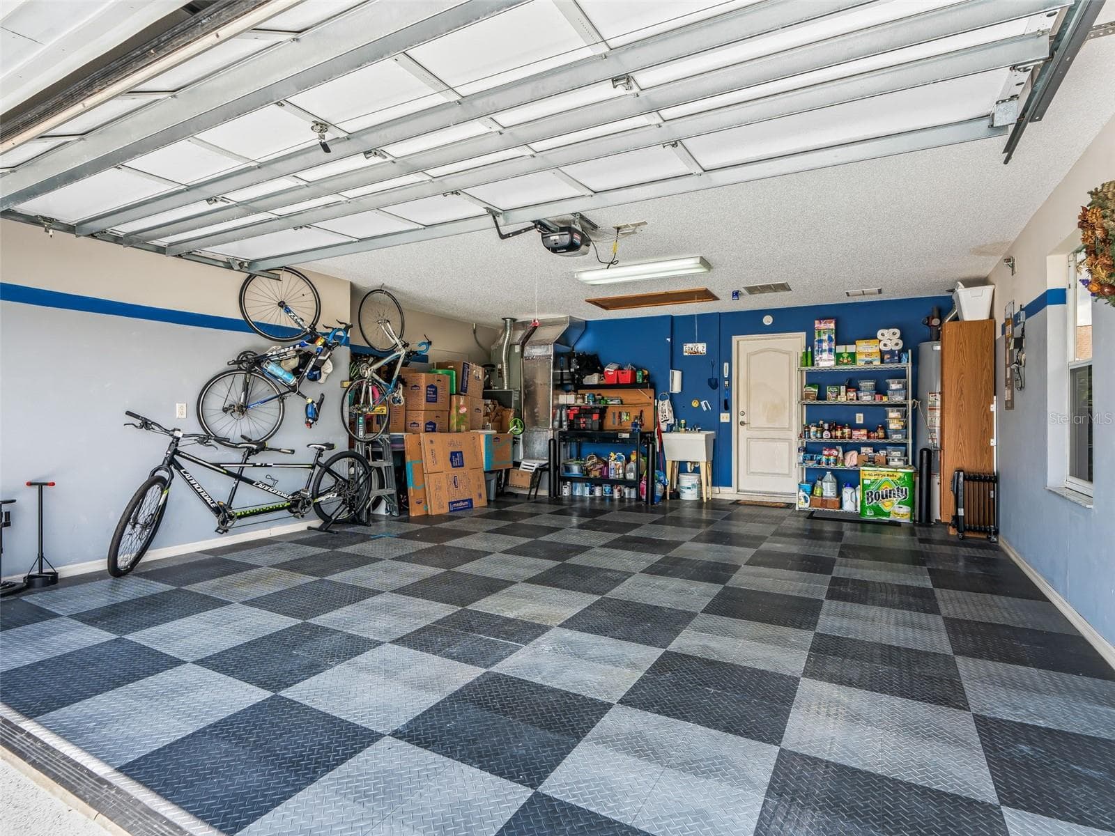 Clean, oversized garage offers abundant storage space, wall-mounted organization, and durable interlocking floor tiles for a polished, easy-care finish. (CLEAN FLOOR UNDERNEATH!) - 17946 SE 87TH MELROSE CT, THE VILLAGES